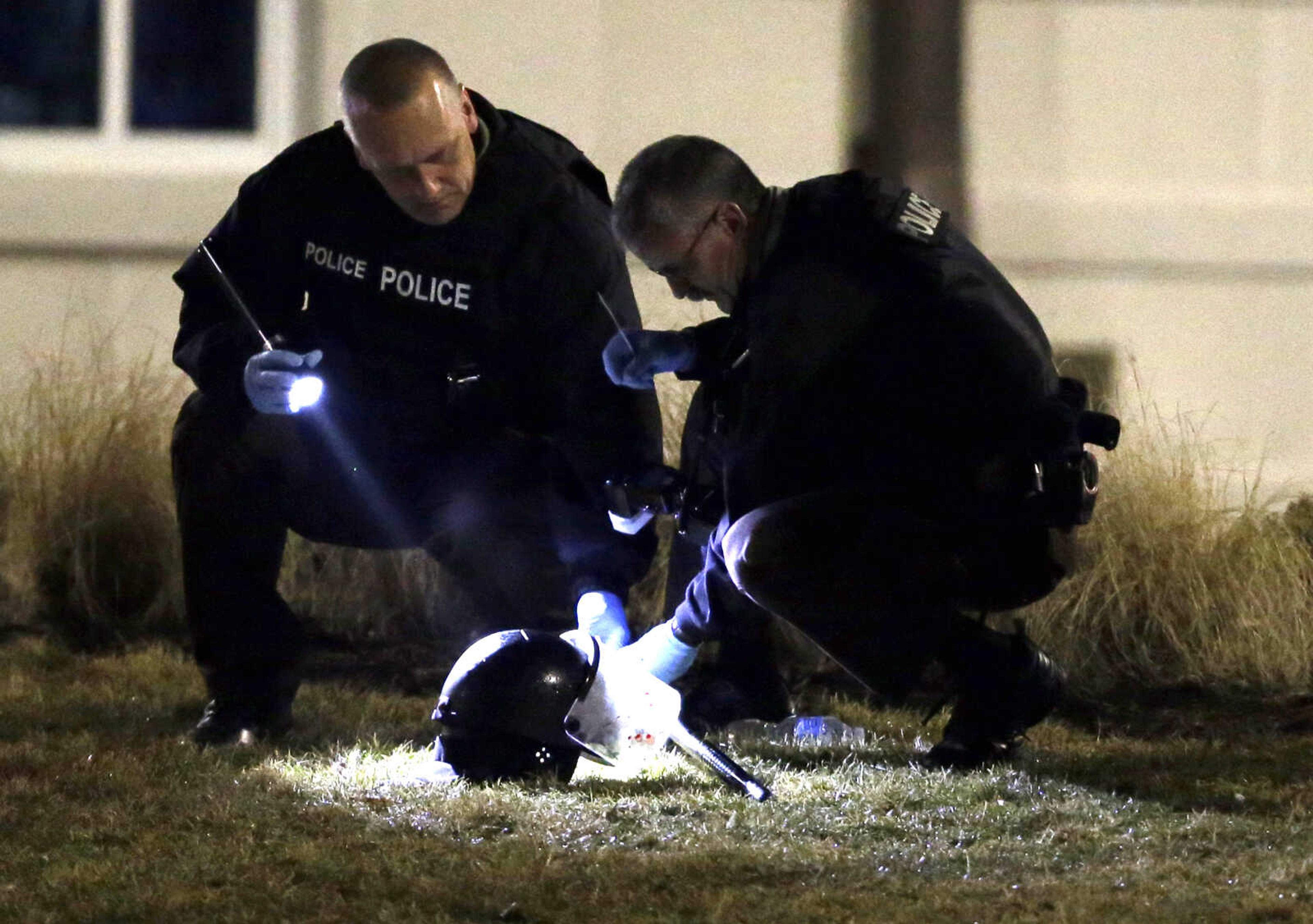 Police shine a light on a helmet as they investigate the scene where two police officers were shot outside the Ferguson Police Department on March 12, 2015, in Ferguson, Missouri.