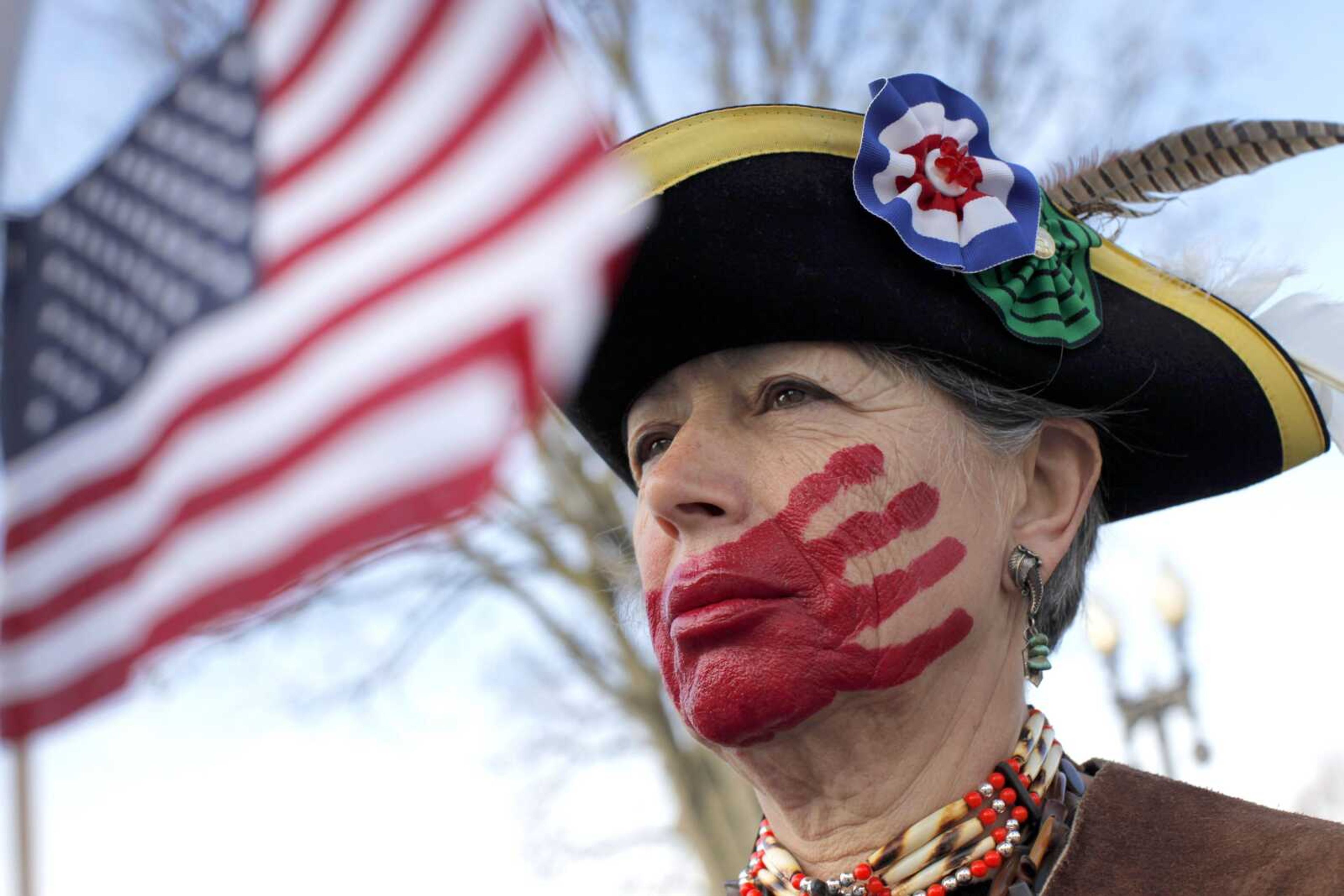 Susan Clark of Santa Monica, Calif., who opposes health care reform, stands Wednesday in front of the Supreme Court in Washington with a red hand painted over her mouth to represent what she said is socialism taking away her choices and rights.<br>Charles Dharapak<br>Associated Press