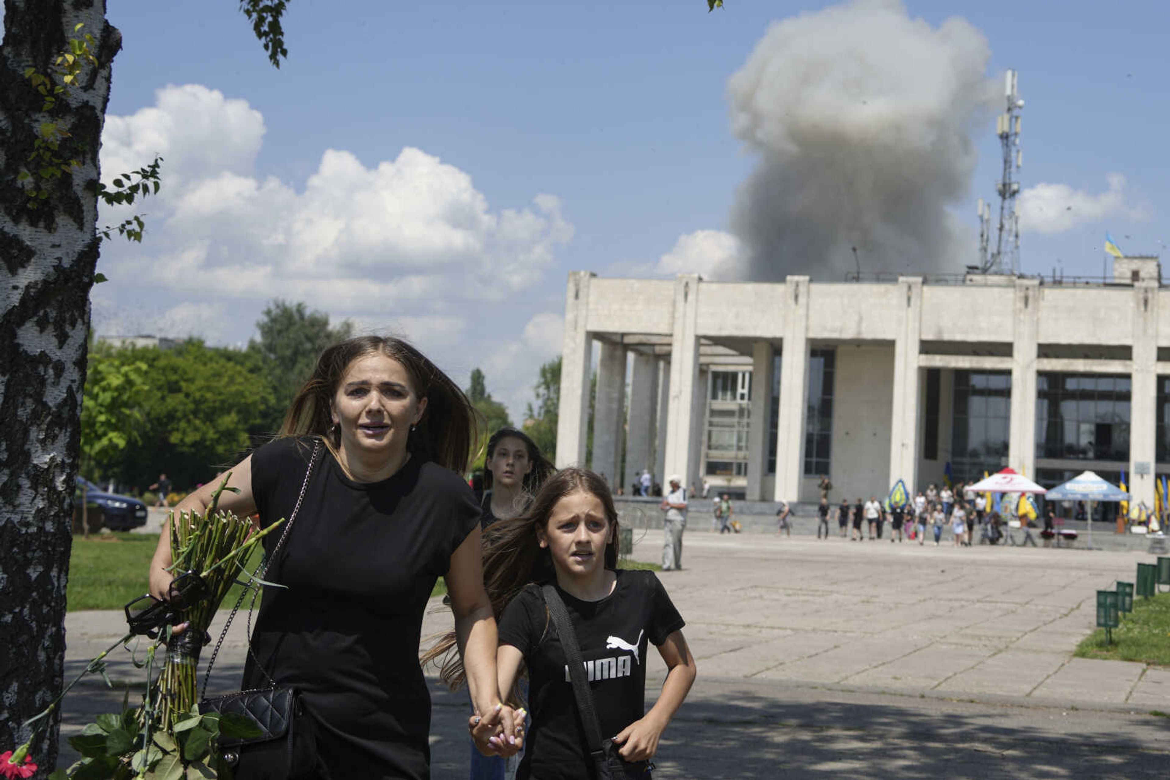 A family runs from an explosion after a Russian rocket attack on a residential neighborhood Tuesday in Pervomaiskyi, Kharkiv region, Ukraine.