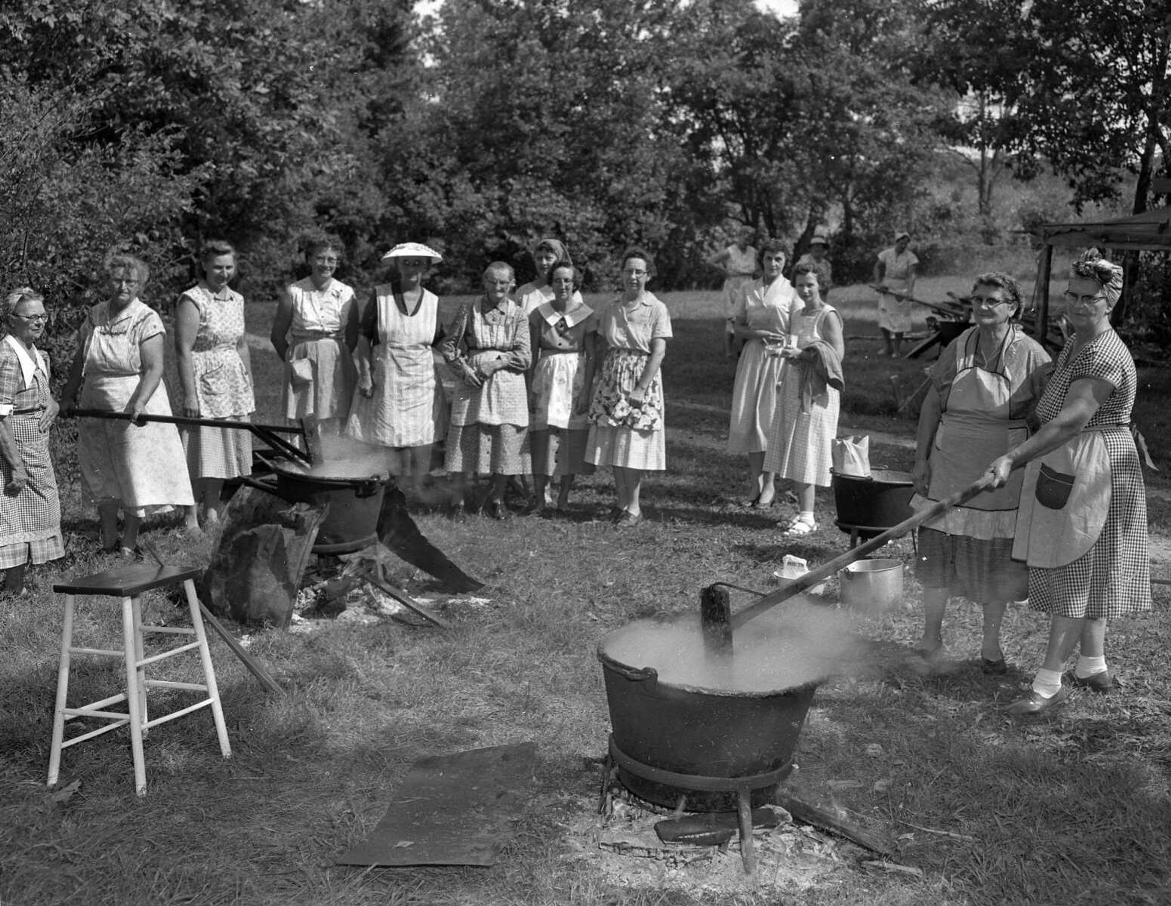 Sept. 11, 1959 Southeast Missourian.
Apple butter time. Members of the Hanover Lutheran Ladies Aid, having disposed of the peach crop, are now working on the first of the apple crop. Using large iron kettles, heated by wood fires, they are turning out in considerable quantity a tasty product they sell, the fund going to build a new kitchen at the church activities building. From the left are Mrs. Lula Meyer, Mrs. Oscar Huettig, Mrs. Martin Meyer, Mrs. Emil Meyer, Mrs. William Opitz, Mrs. Adam Frank, Mrs. Ervin Frank, Mrs. E.C. Mullen, Mrs. E.F. Overbeck, Mrs. Louis Weiss, Mrs. Ervin Frank Jr., Mrs. Linda Niemeier and Mrs. Louis Gerecke. The picture was made Thursday. (G.D. Fronabarger/Southeast Missourian archive)