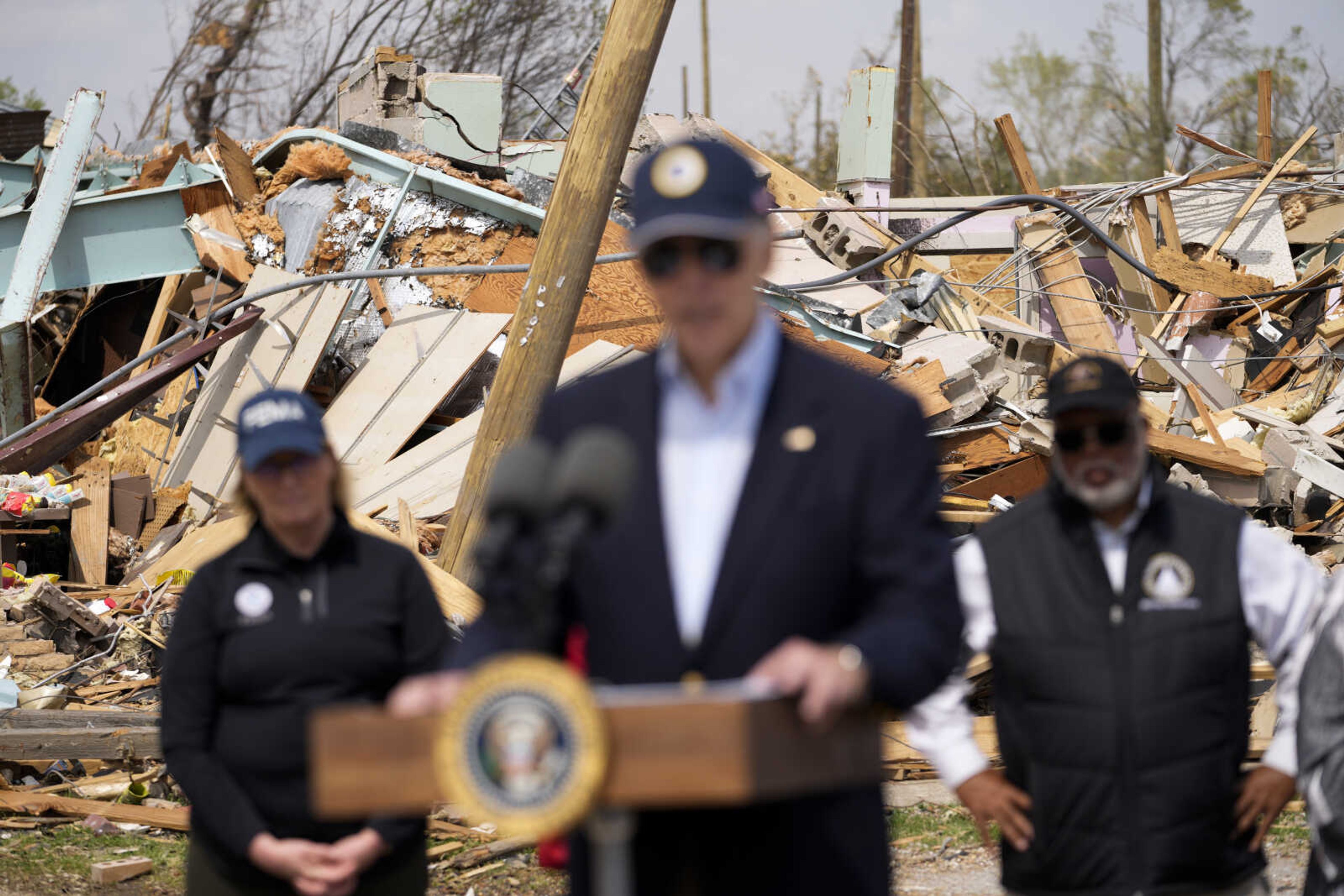 President Joe Biden speaks after surveying the damage in Rolling Fork, Miss., Friday, March 31, 2023, after a deadly tornado and severe storm moved through the area. FEMA Administrator Deanne Criswell, left, and Rep. Bennie Thompson, D-Miss., right, listen. (AP Photo/Carolyn Kaster)