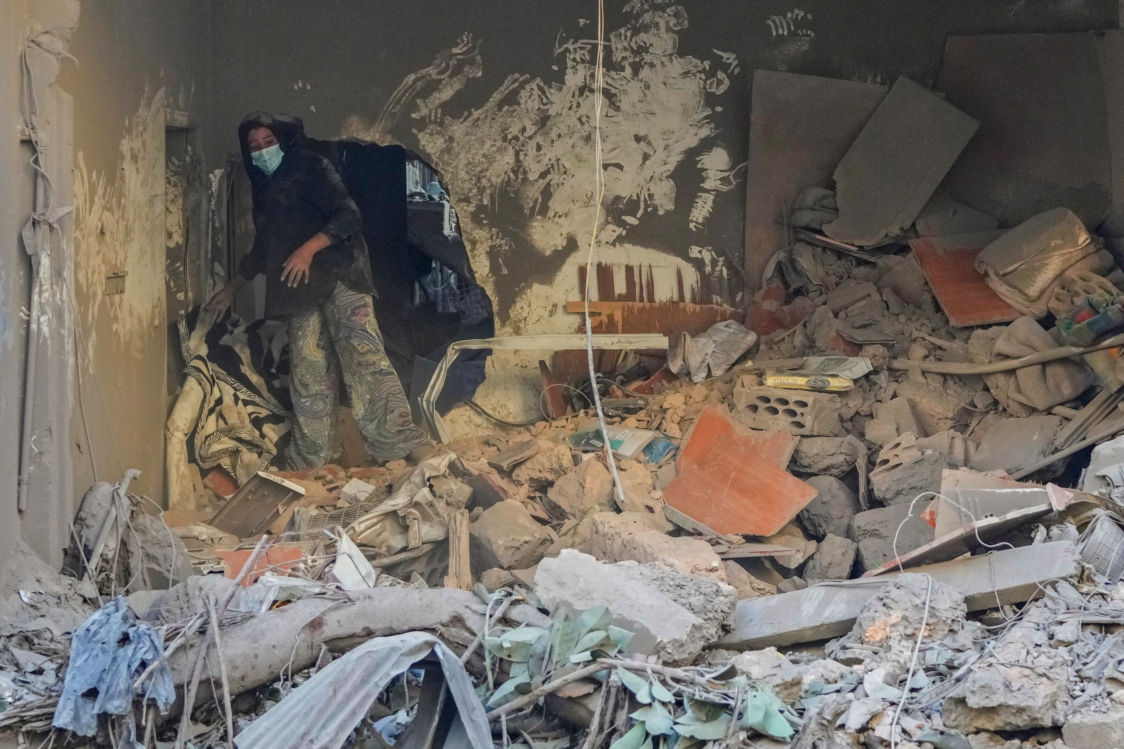 A resident of a building damaged in an Israeli airstrike returns to collect her family's belongings at the site of Thursday's Israeli airstrike in Beirut, Lebanon, Friday, Oct. 11, 2024. (AP Photo/Hassan Ammar)