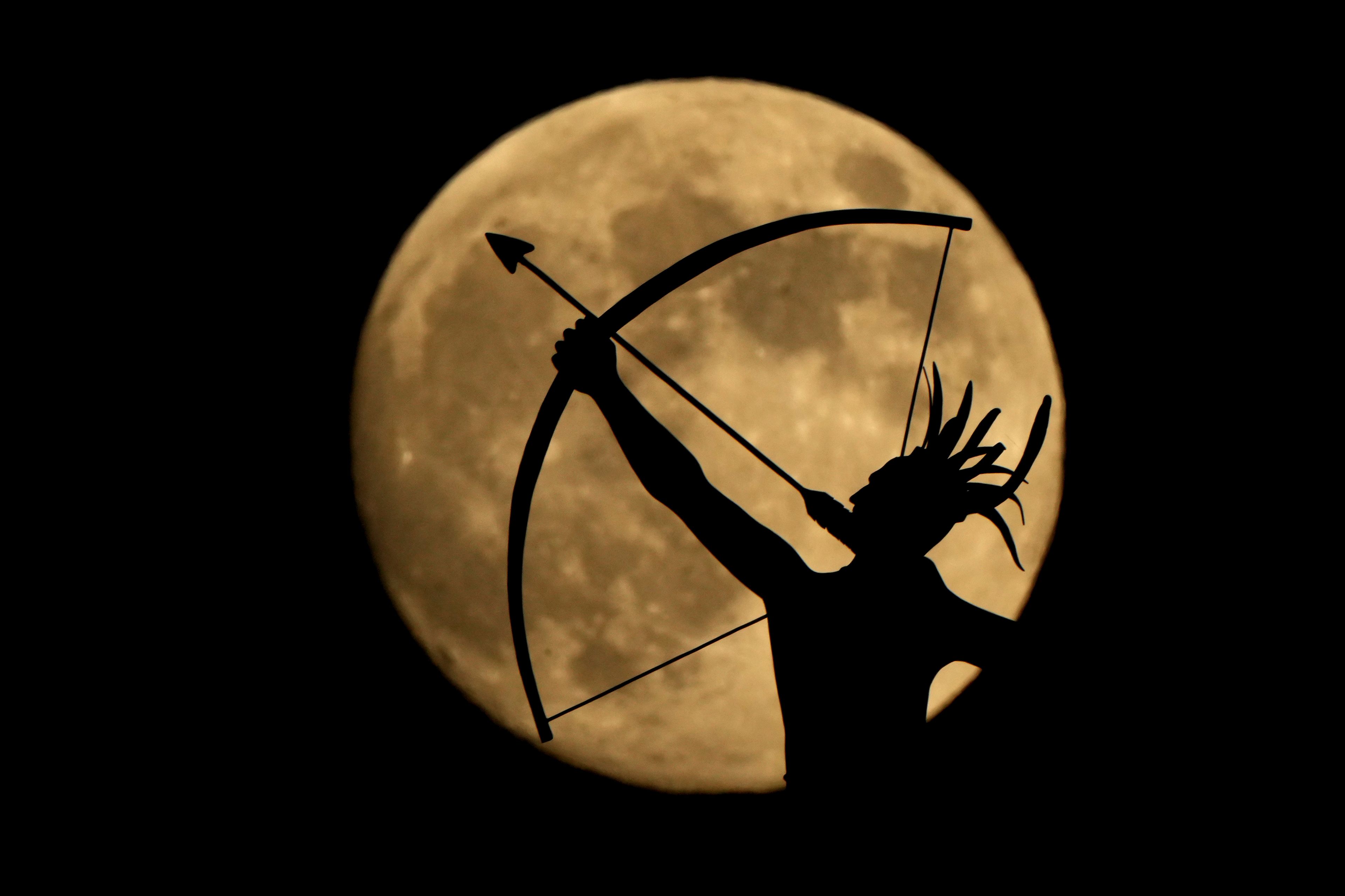 A bronze sculpture of "Ad Astra" a Kansa Indian, perched atop the Kansas Capitol dome is silhouetted against the nearly full moon Thursday, Nov. 14, 2024, on the eve of the final supermoon of the year in Topeka, Kan. (AP Photo/Charlie Riedel)