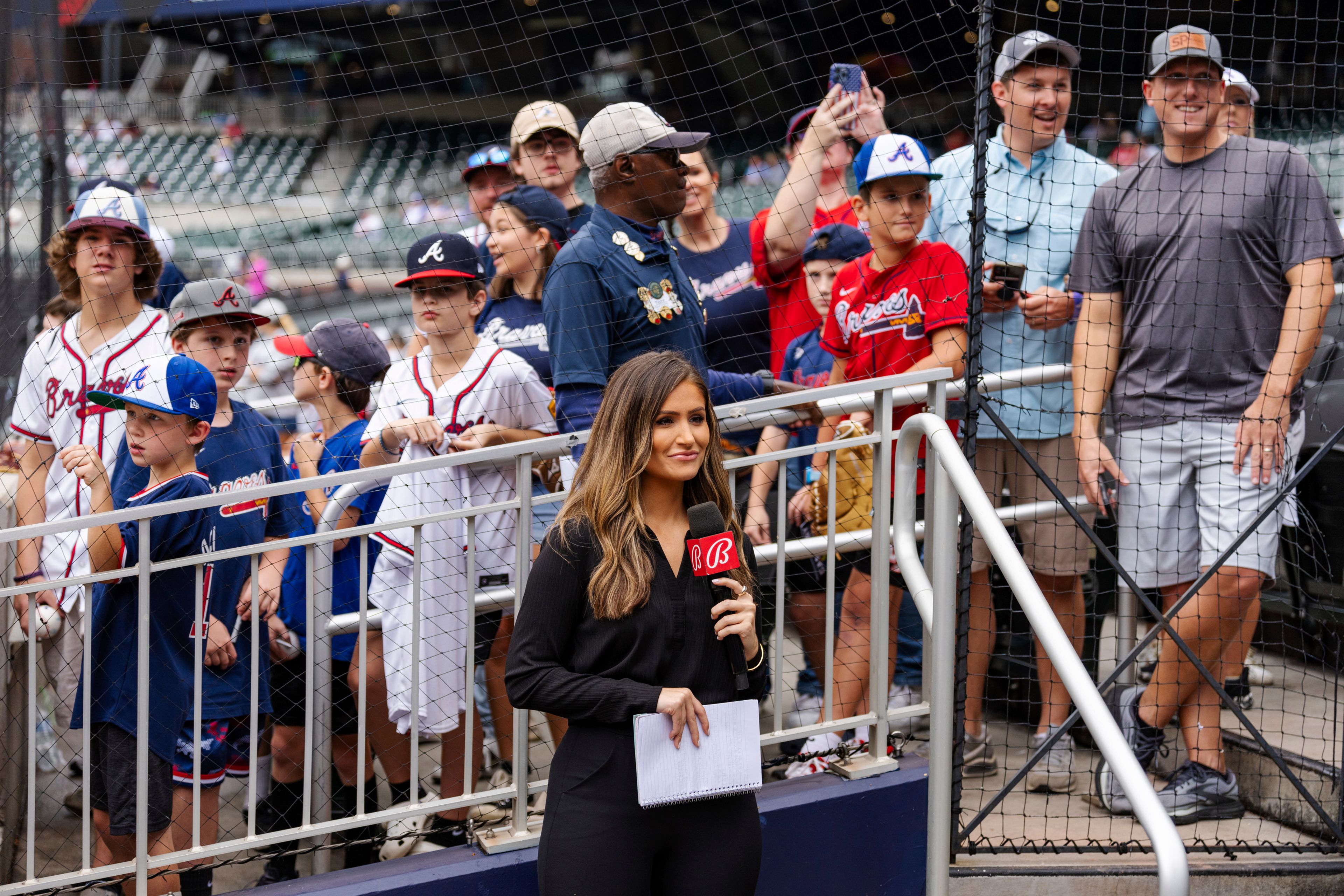 Bally reporter, Hanna Yates, broadcasts her pregame with fans standing behind her waiting for autographs before the start of a baseball game between the New York Mets and the Atlanta Braves, Monday, Sept. 30, 2024, in Atlanta. (AP Photo/Jason Allen)