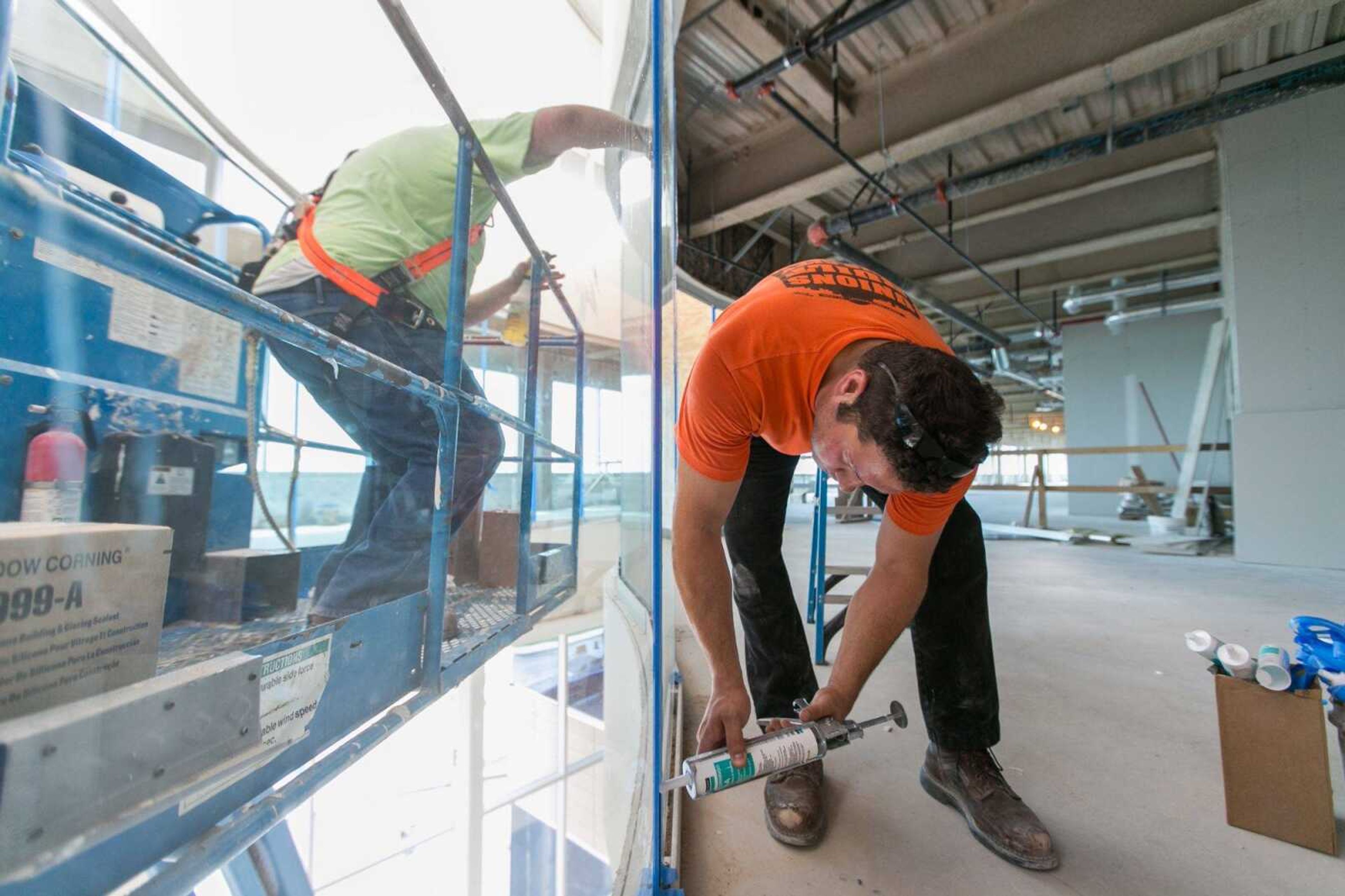 Gary Murvai, left, and Adam Losh fill the gaps between window panes with silicone April 29 on the fifth floor of the atrium at the new main entrance to Saint Francis Medical Center. (Glenn Landberg)