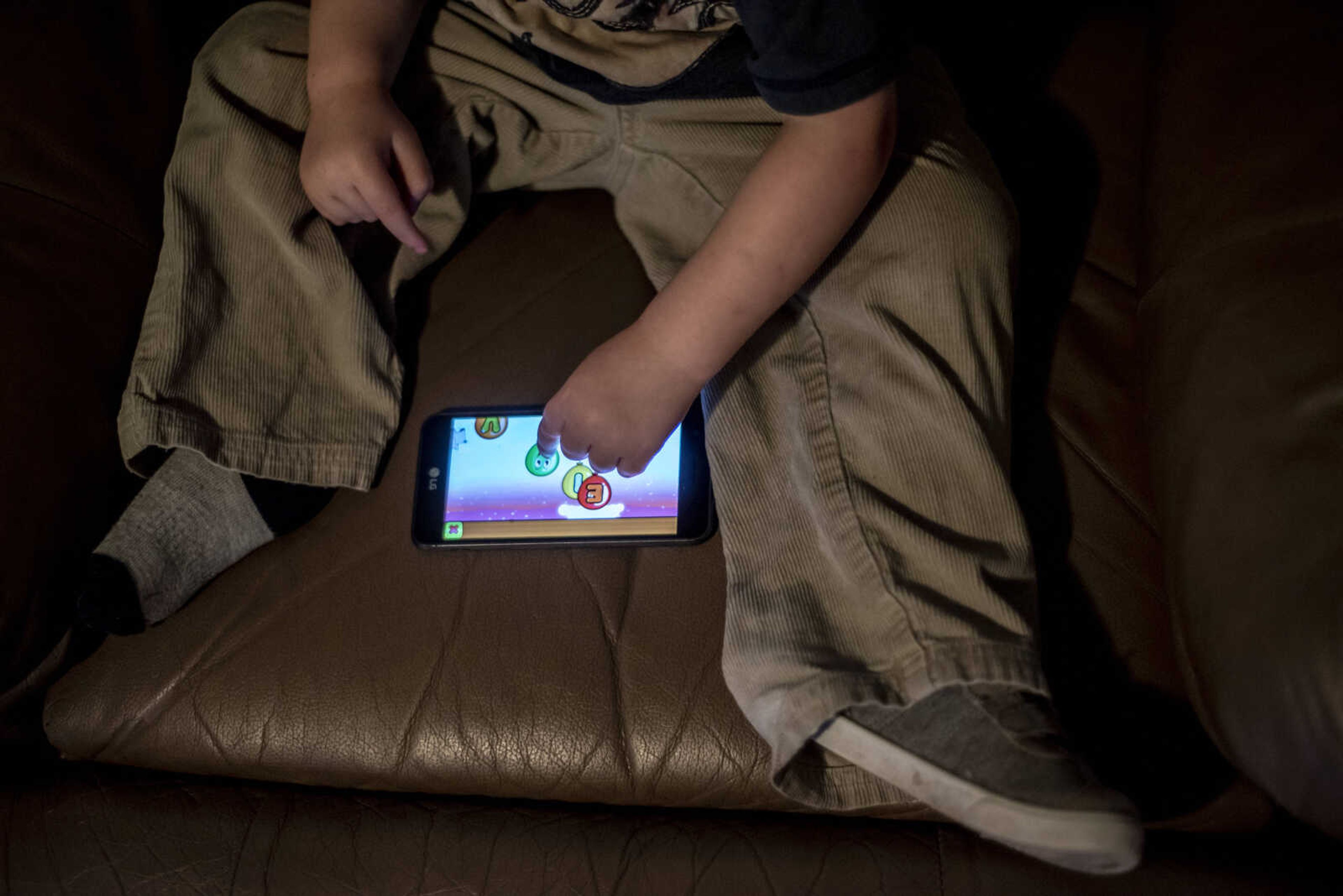 Phoenix Young, 2, plays a game on a cell phone while being occupied so his mom and other members of his family can get ready for his mom, Emily Medlock's, high school graduation Sunday, May 12, 2019, in Cape Girardeau.