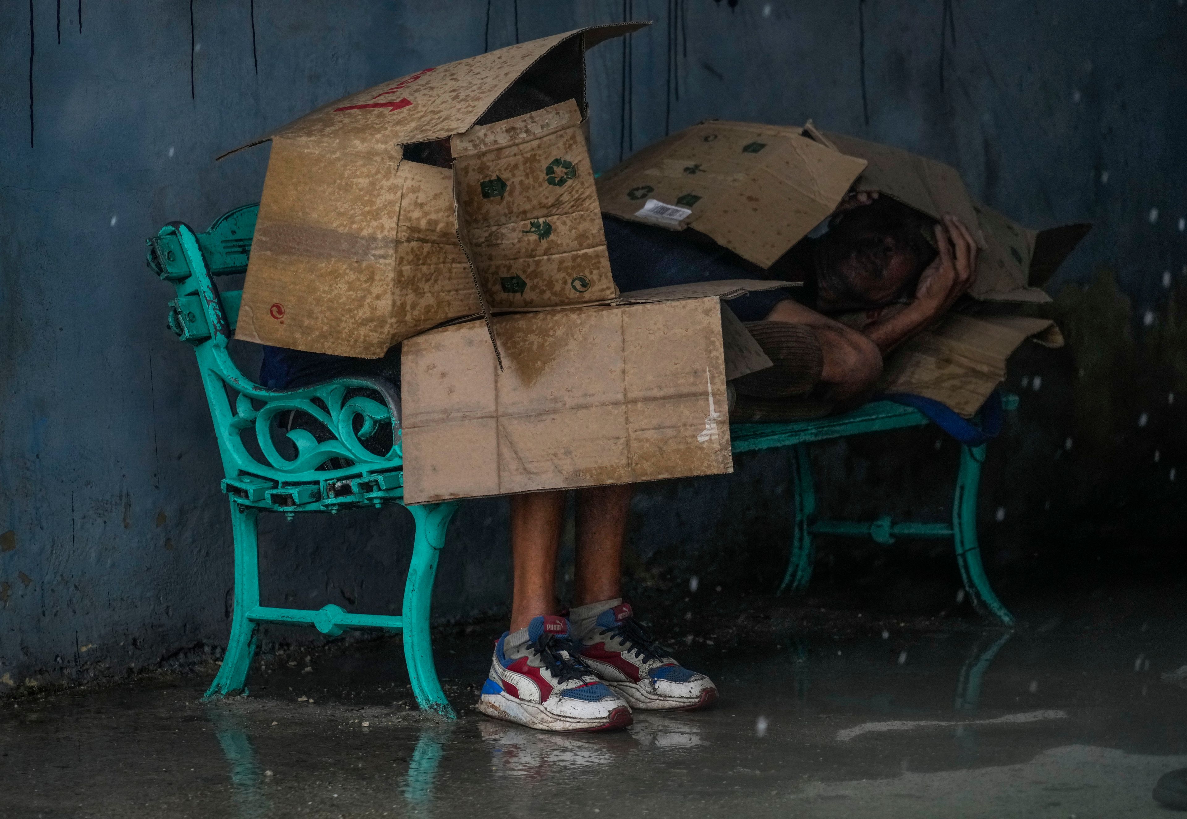 People at a bus stop shield themselves with cardboard amid wind and rain during the passage of Hurricane Rafael in Havana, Cuba, Wednesday, Nov. 6, 2024. (AP Photo/Ramon Espinosa)