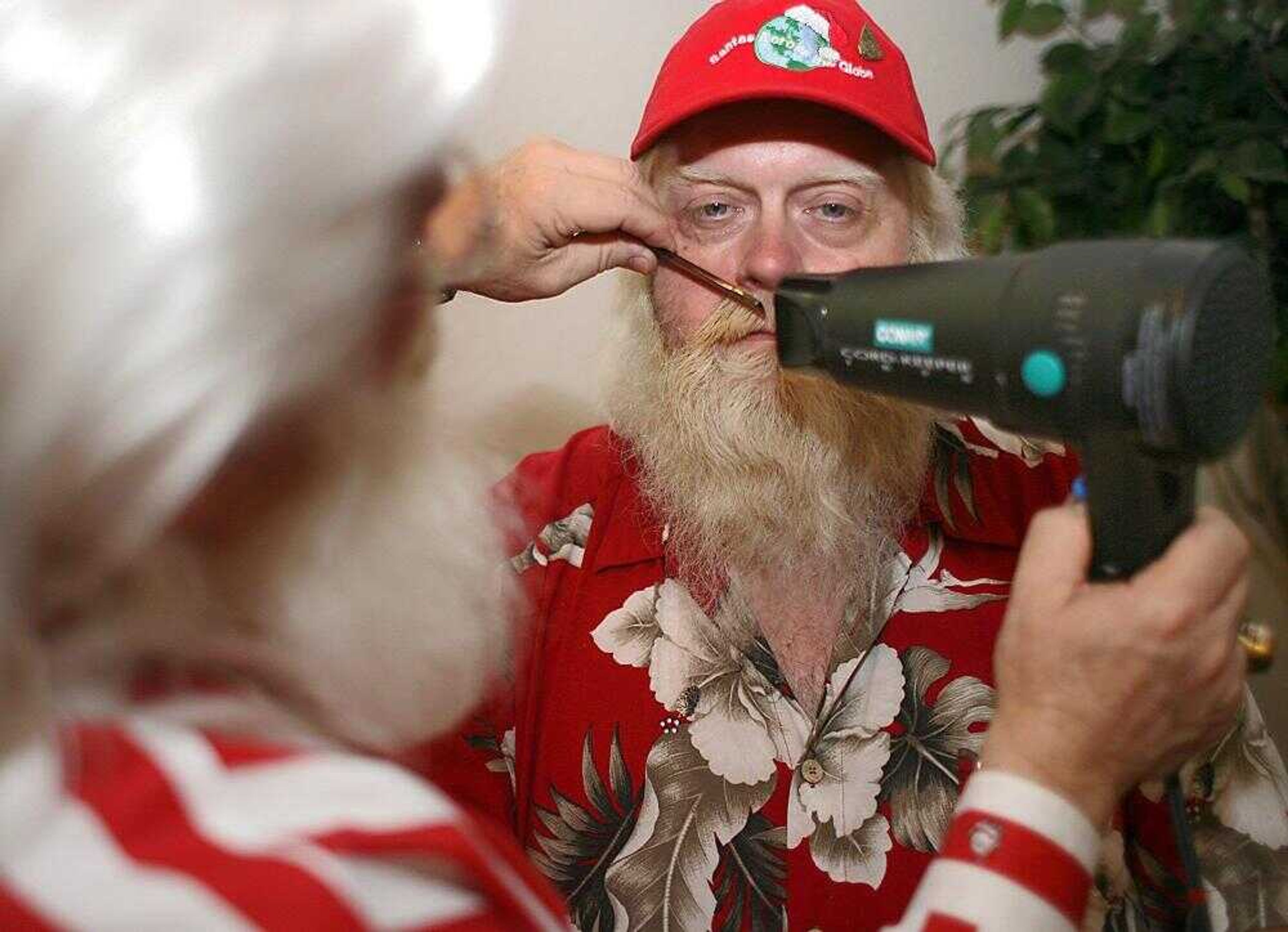 Santa Timothy Connaghan, left, instructor of School 4 Santas, styled the mustache of Santa Owen Davenport of Terre Haute, Ind., Saturday during the workshop at the La Quinta Inn in Hazelwood, Mo. This weekend, about 20 of those Santas gathered at a hotel in the St. Louis suburb of Hazelwood to learn from the International University of Santa Claus, a traveling school that helps Santas brush up on their techniques. (SARAH CONARD ~ St. Louis Post-Dispatch)