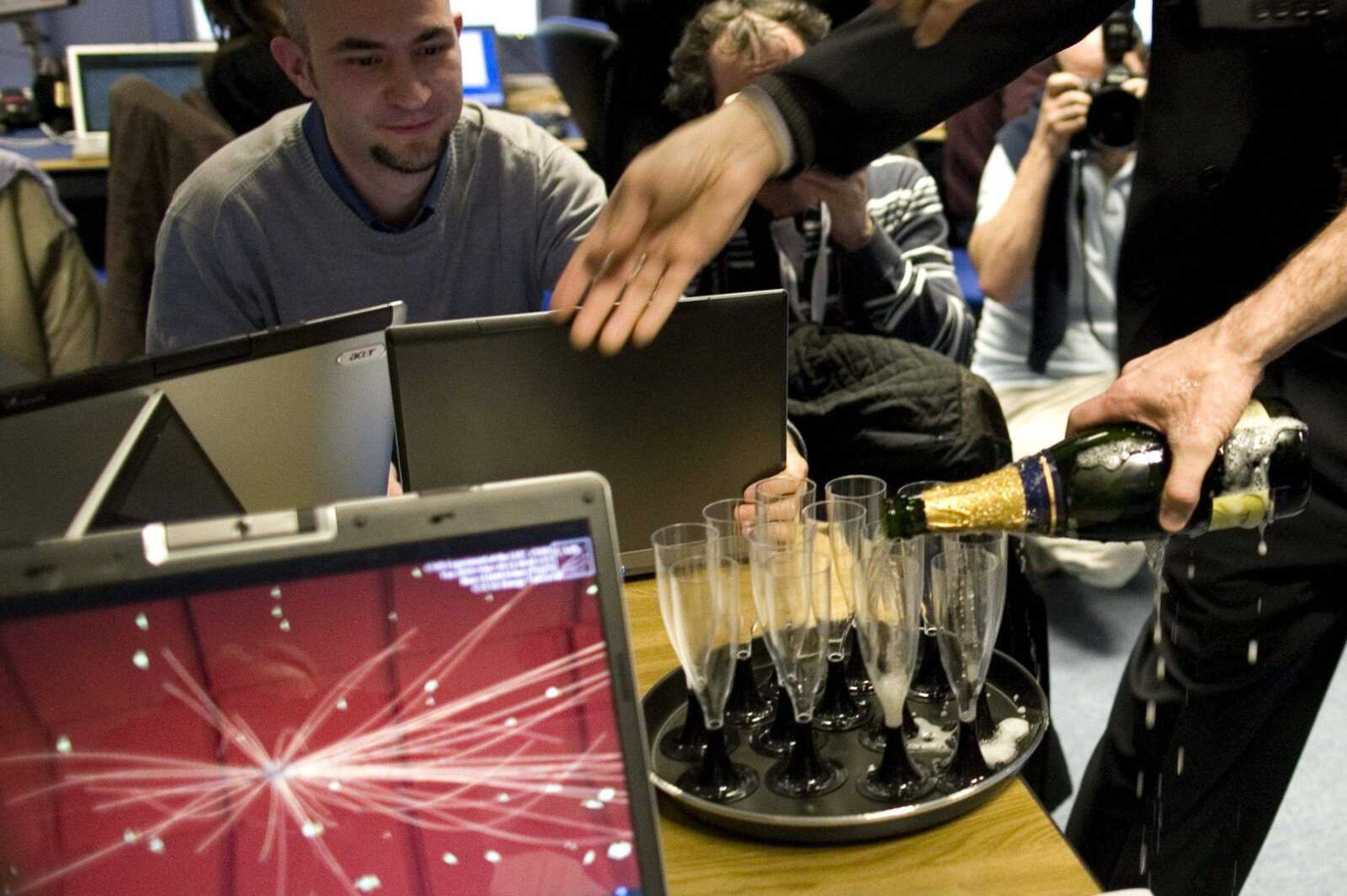 Scientists of the European Organization for Nuclear Research, CERN, celebrate with champagne Tuesday at their headquarters outside Geneva. The world's largest atom smasher set a record for high-energy collisions by crashing two proton beams at three times more force than ever before. (Anja Niedringhaus ~ Associated Press)