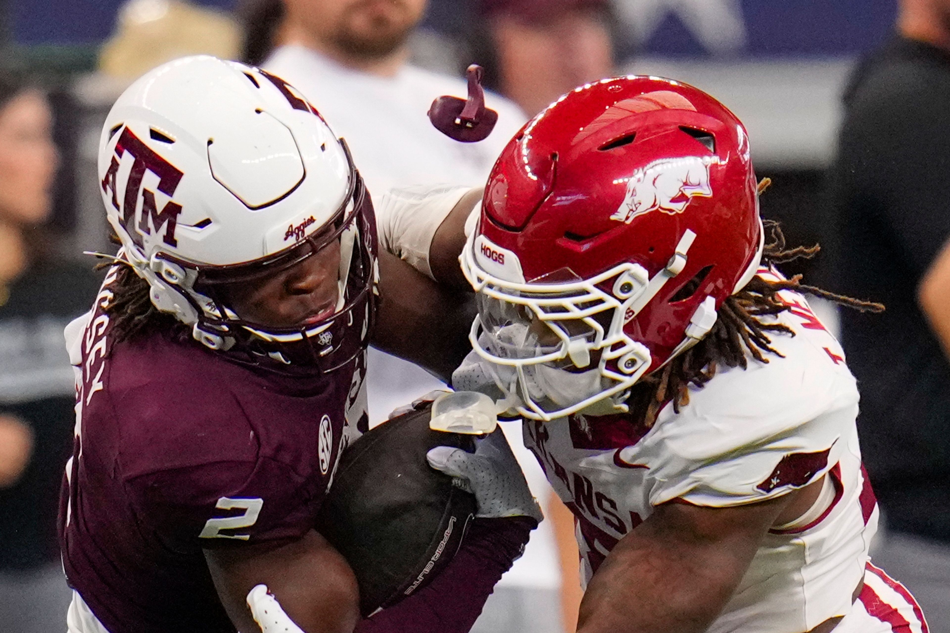 The mouthpiece of Texas A&M running back Rueben Owens, left, goes flying after taking a hit from Arkansas defensive back TJ Metcalf during the second half of an NCAA college football game, Saturday, Sept. 28, 2024, in Arlington, Texas. Texas A&M won 21-17. (AP Photo/Julio Cortez)