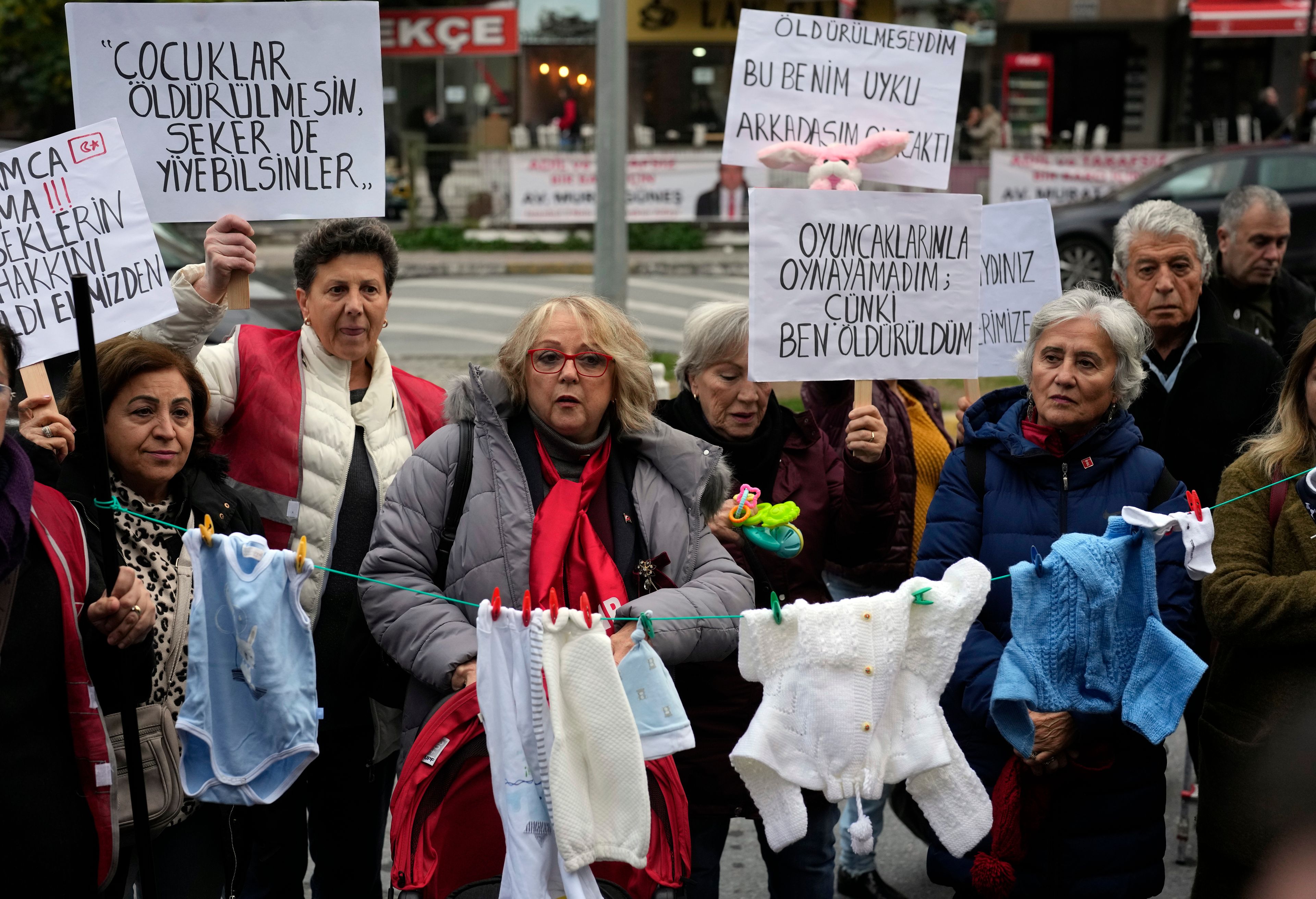 Activists some holding banners with Turkish writing that read, " Children should not be killed , so they can eat candies", " I couldn't play with my toys because I was killed" and " If I had not been killed this toy would have been my sleeping friend " during a protest outside the courthouse where dozens of Turkish healthcare workers including doctors and nurses go on trial for fraud and causing the deaths of 10 infants, in Istanbul, Turkey, Monday Nov, 18, 2024.(AP Photo/Khalil Hamra)