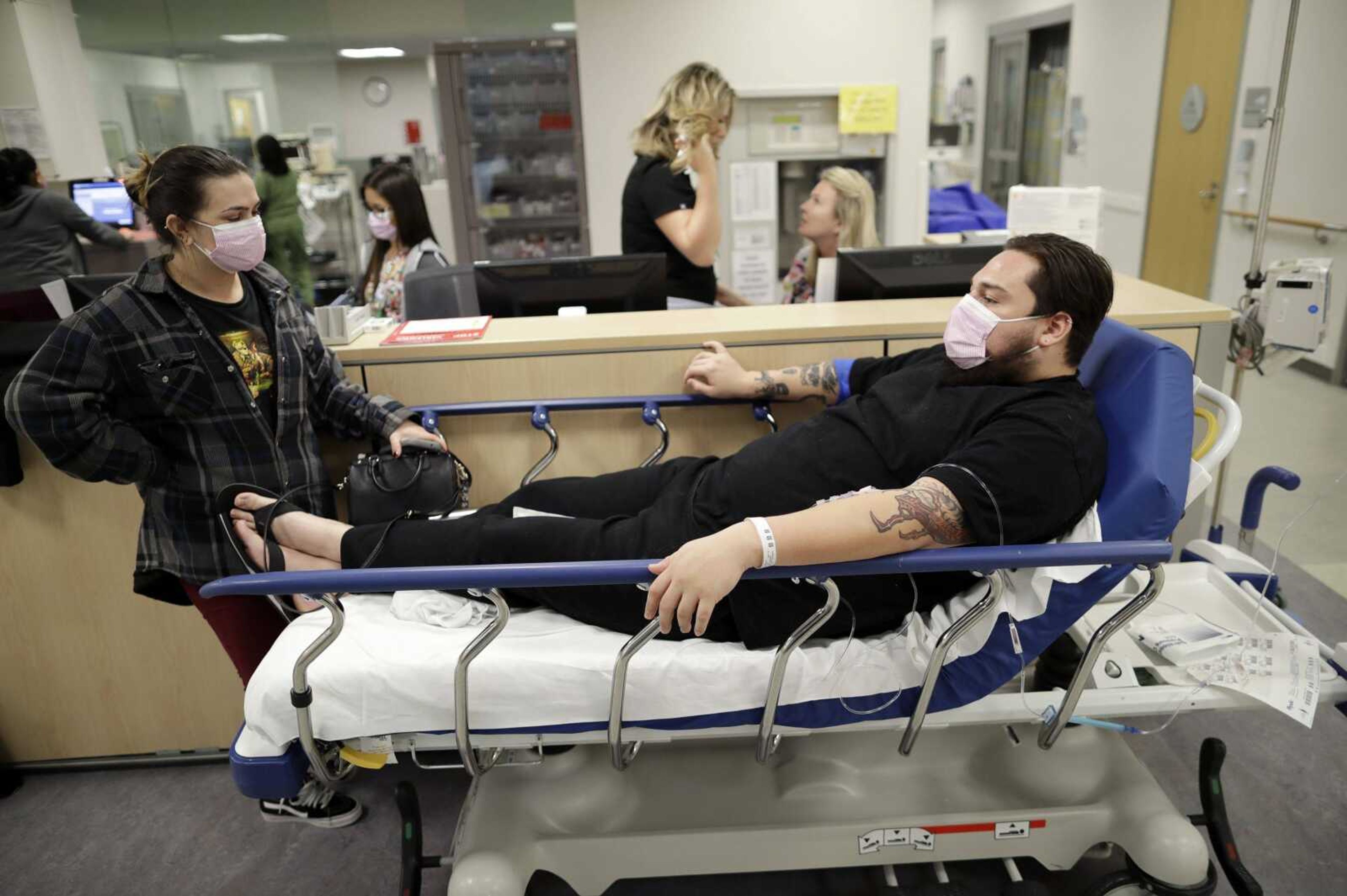 Donnie Cardenas, right, waits in an emergency-room hallway alongside roommate Torrey Jewett, left, as he recovers from the flu Wednesday at the Palomar Medical Center in Escondido, California.