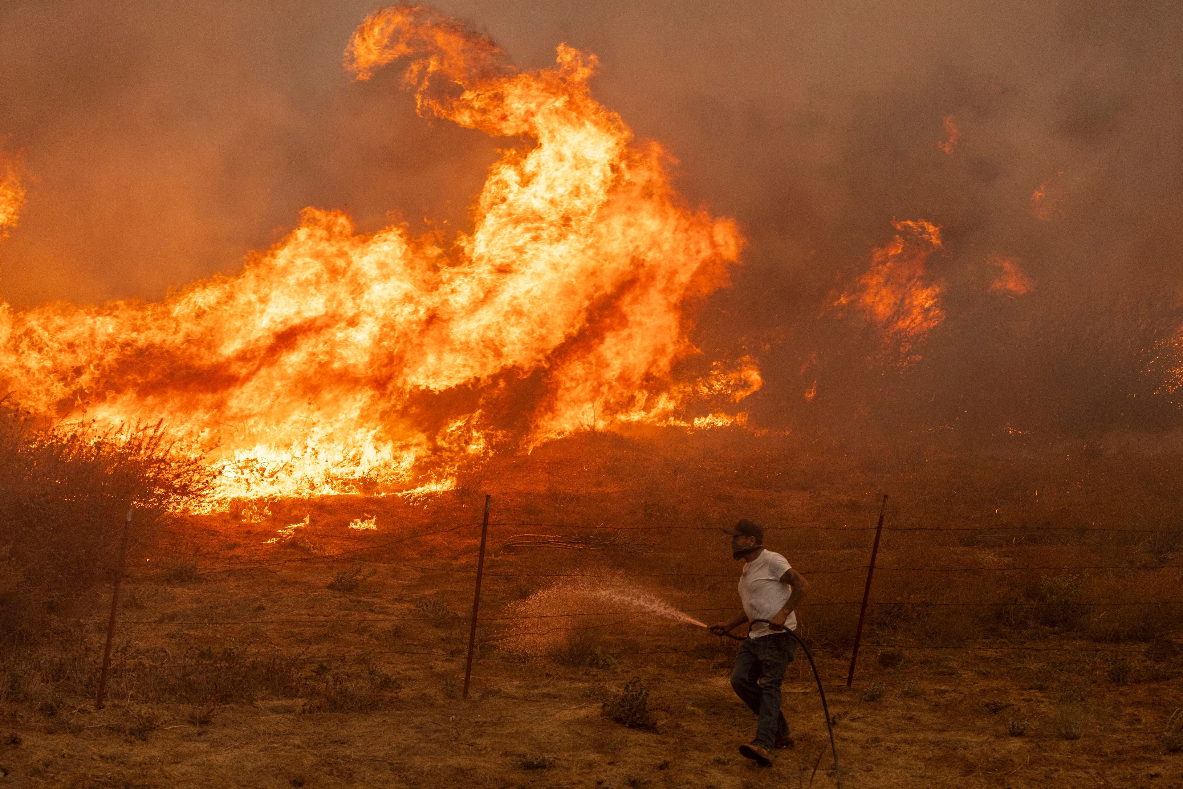 Jaime Hernandez sprays water to defend his home while battling approaching flames from the Mountain Fire near Moorpark, Calif., Nov. 7, 2024. Hernandez has been staying behind to fight multiple wildfires since 1988. (Stephen Lam/San Francisco Chronicle via AP)