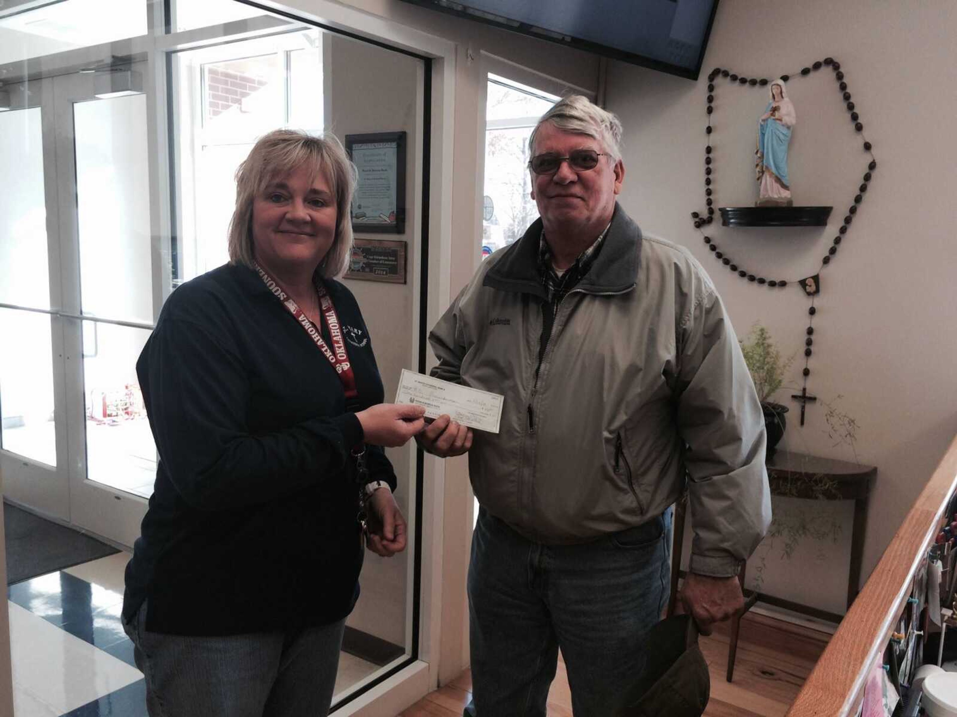 Mr Breunderman accepts a check from Mrs Amy Kirchfoerfer at St Mary Cathedral School.