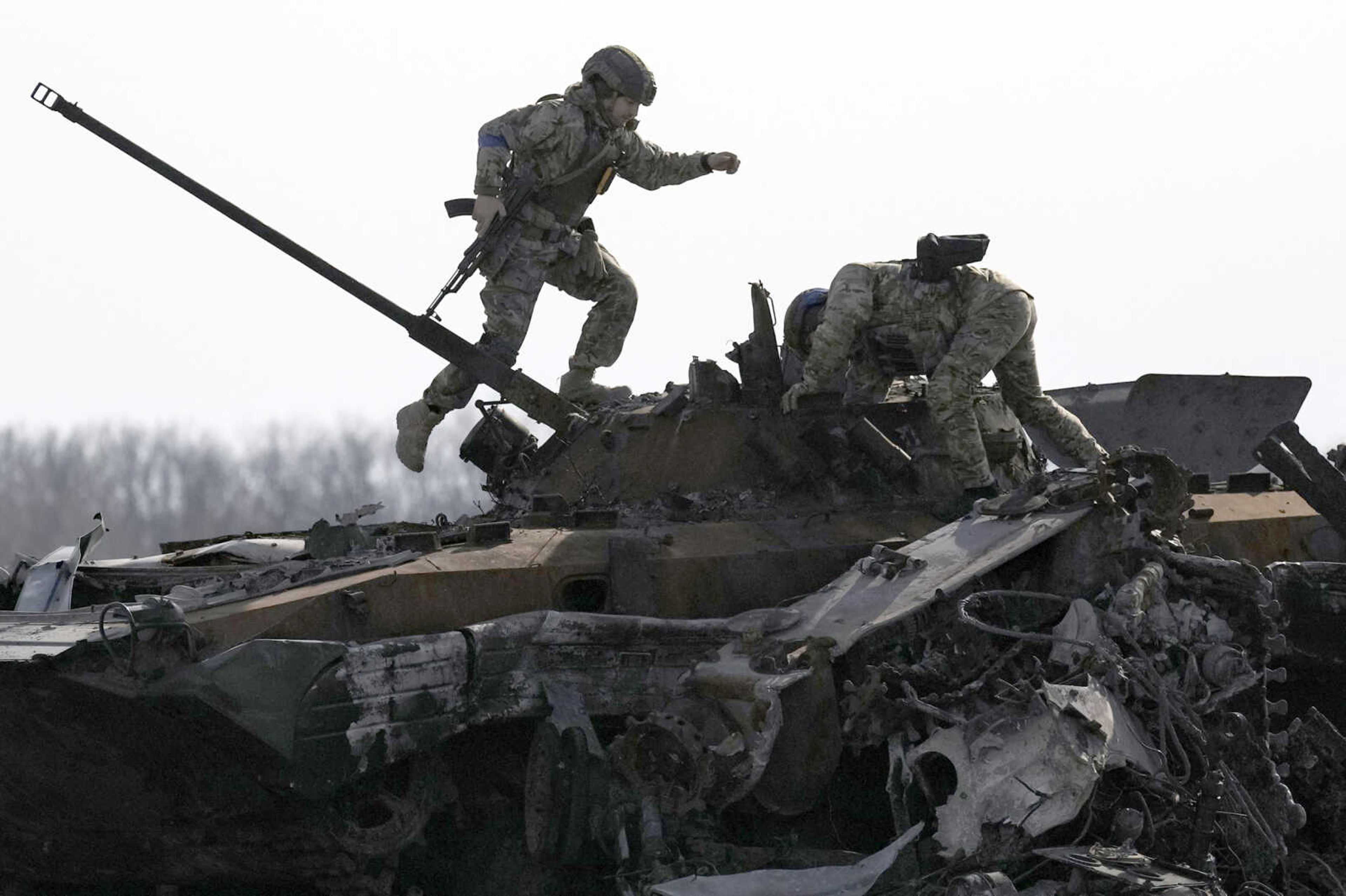 A Ukrainian serviceman walks on a destroyed Russian fighting vehicle Thursday in Bucha, Ukraine. Russian troops left behind crushed buildings, streets littered with destroyed cars and residents in dire need of food and other aid in a northern Ukrainian city, giving fuel to Kyiv's calls Thursday for more Western support to help halt Moscow's offensive before it refocuses on the country's east.