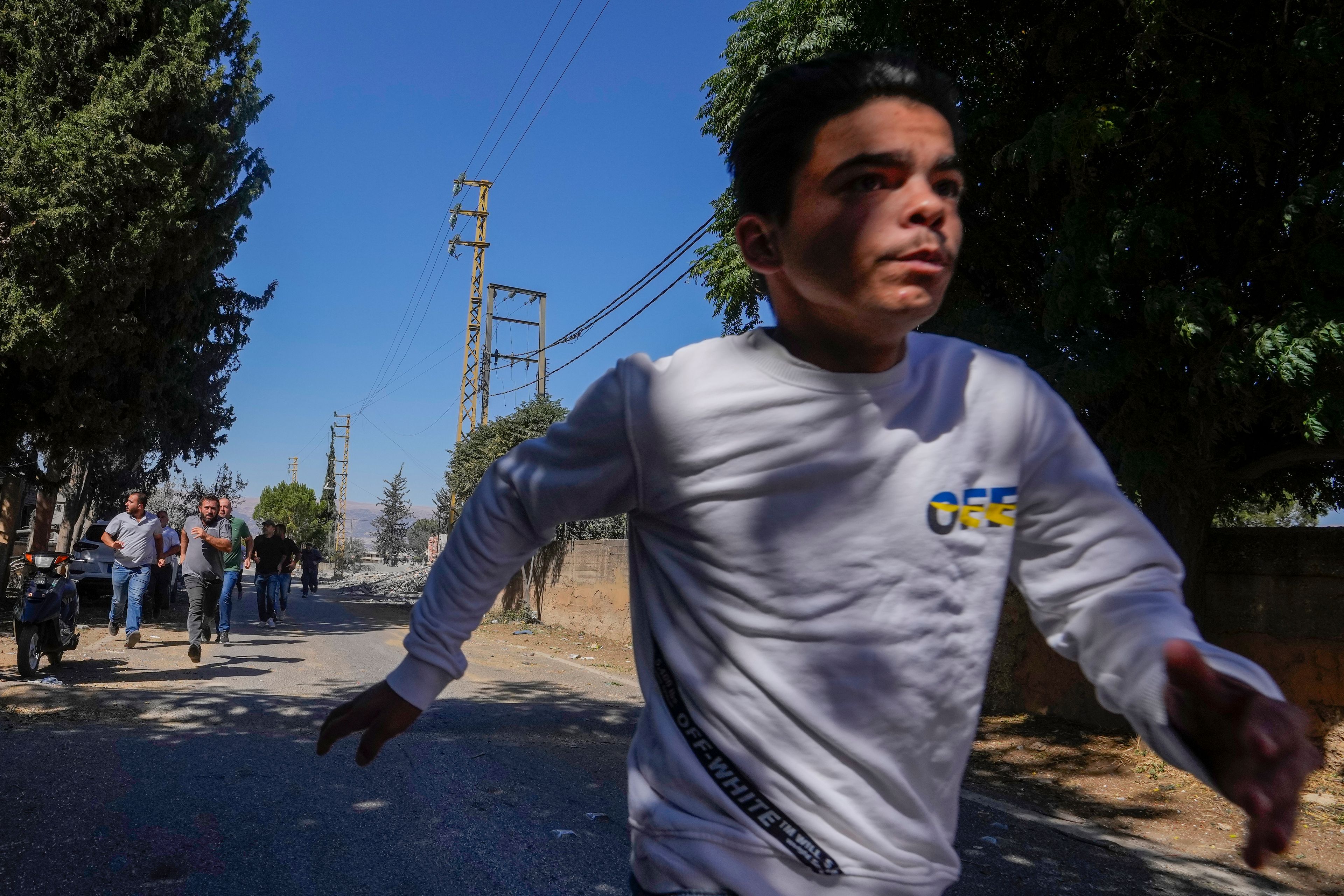 Journalists and residents run for cover following an Israeli airstrike in Baalbek, east Lebanon, Sunday, Oct. 6, 2024. (AP Photo/Hassan Ammar)