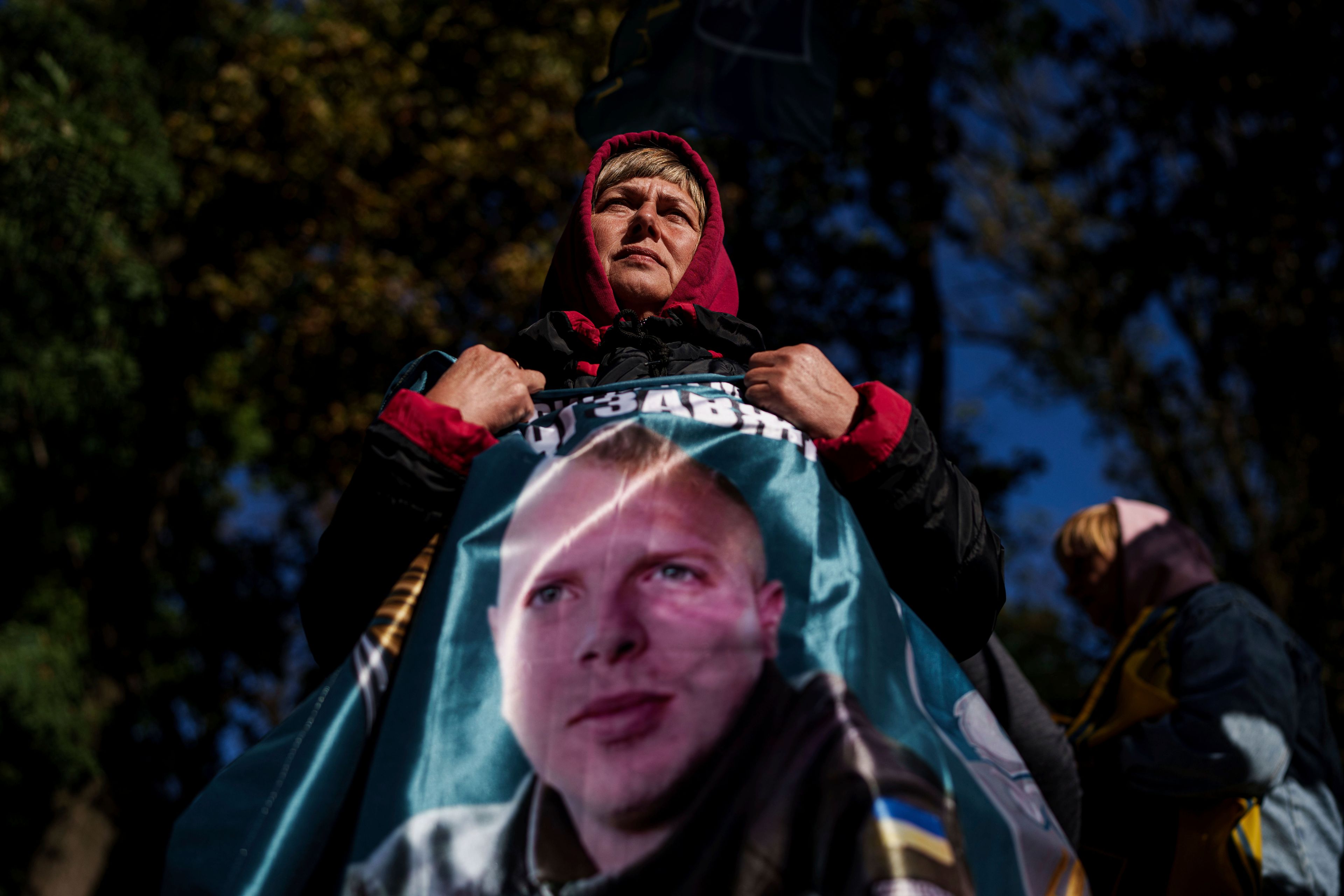 Svetlana holds a flag with a photo of her son Andrii Savchuk, a Ukrainian officer of the 36th marine brigade, during a gathering in support of soldiers who defended Mariupol and are still in Russian captivity after two and half years, in Kyiv, Ukraine, Wednesday, Oct. 9, 2024. (AP Photo/Evgeniy Maloletka)