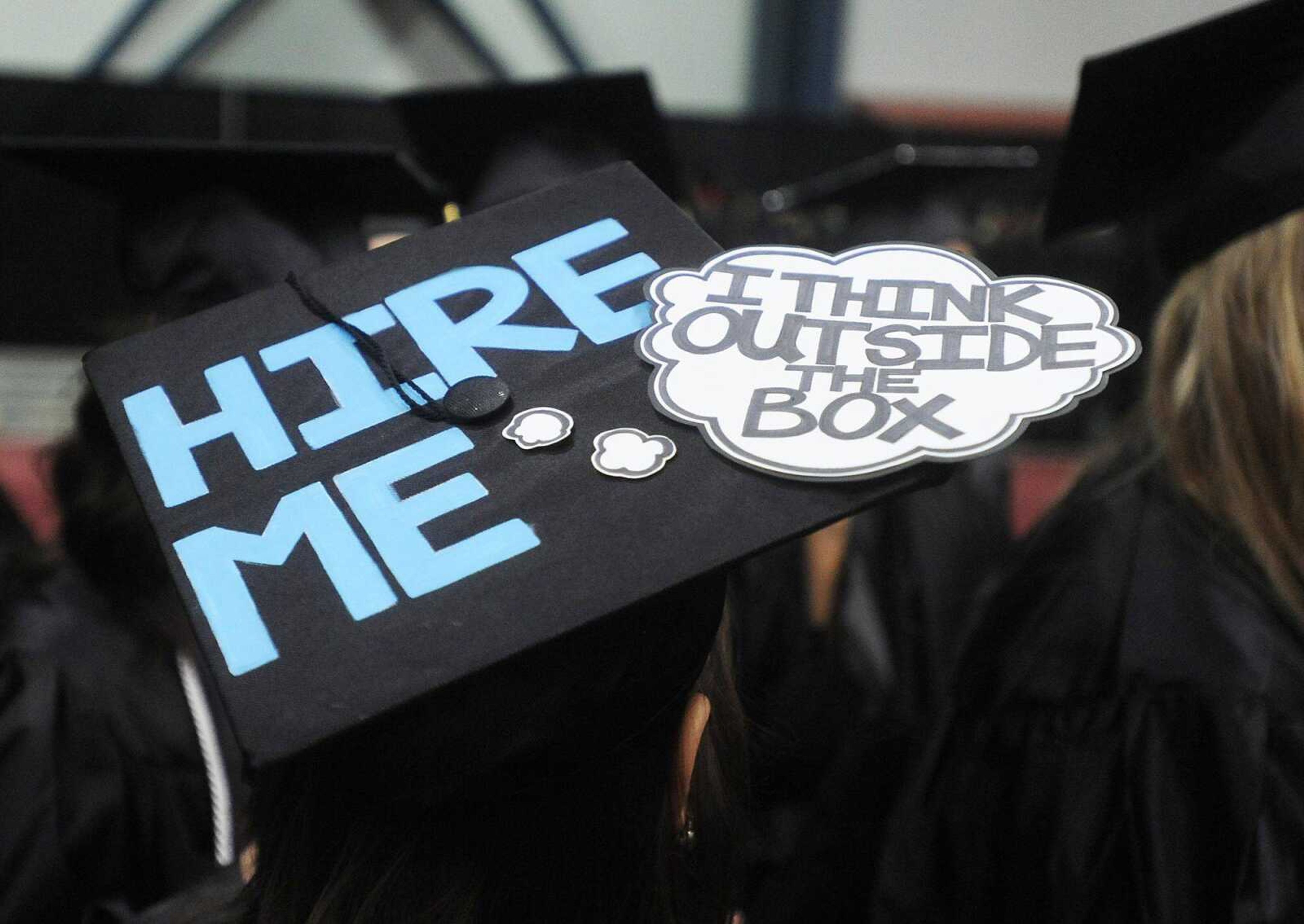 Southeast Missouri State University graduate Abby Menke uses her mortar board to start her post-graduation job search before the 2013 Spring Commencement ceremony Saturday at the Show Me Center. (ADAM VOGLER)