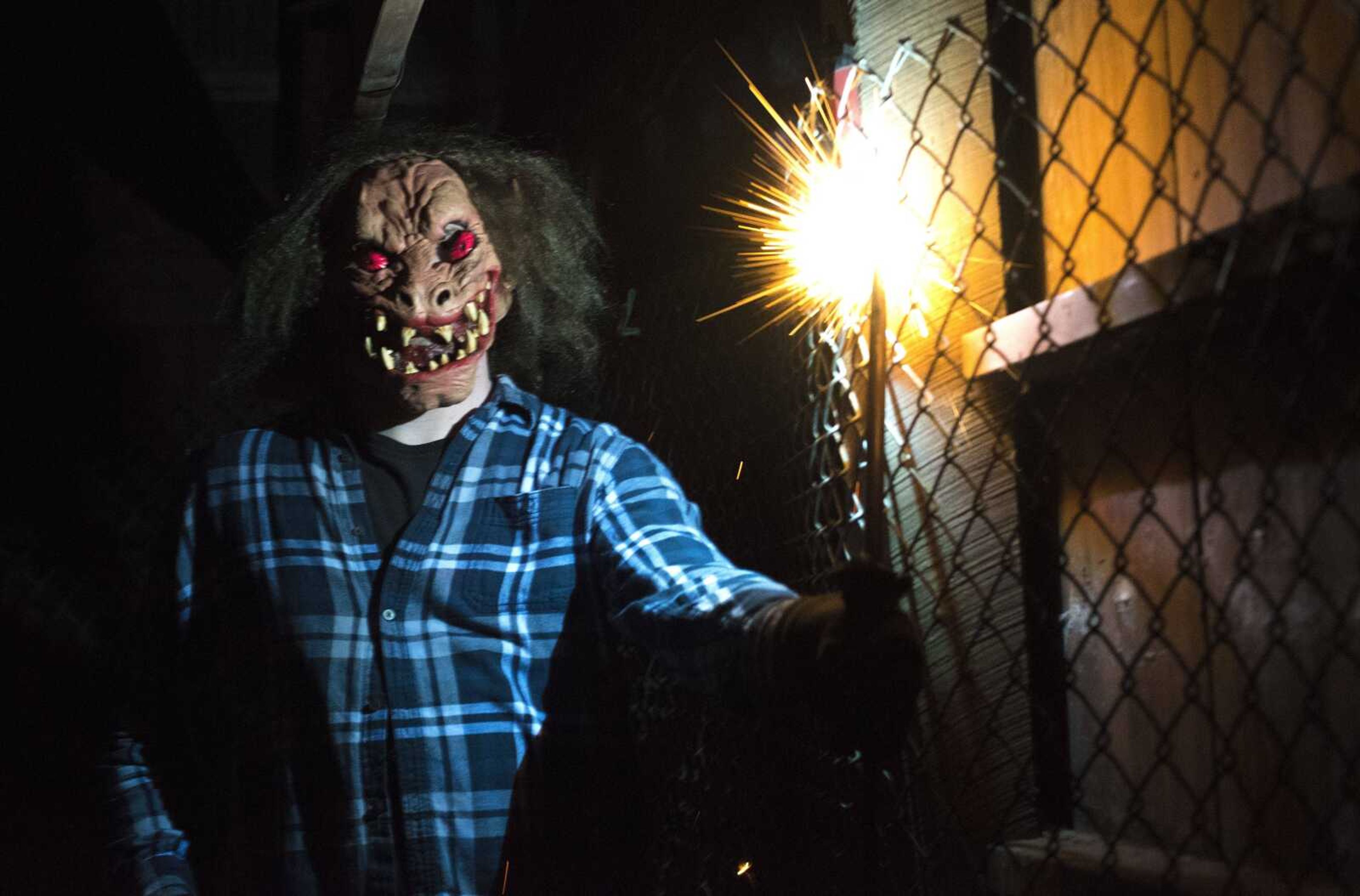 An actor creates sparks to scare guests inside the Tool Shed building.