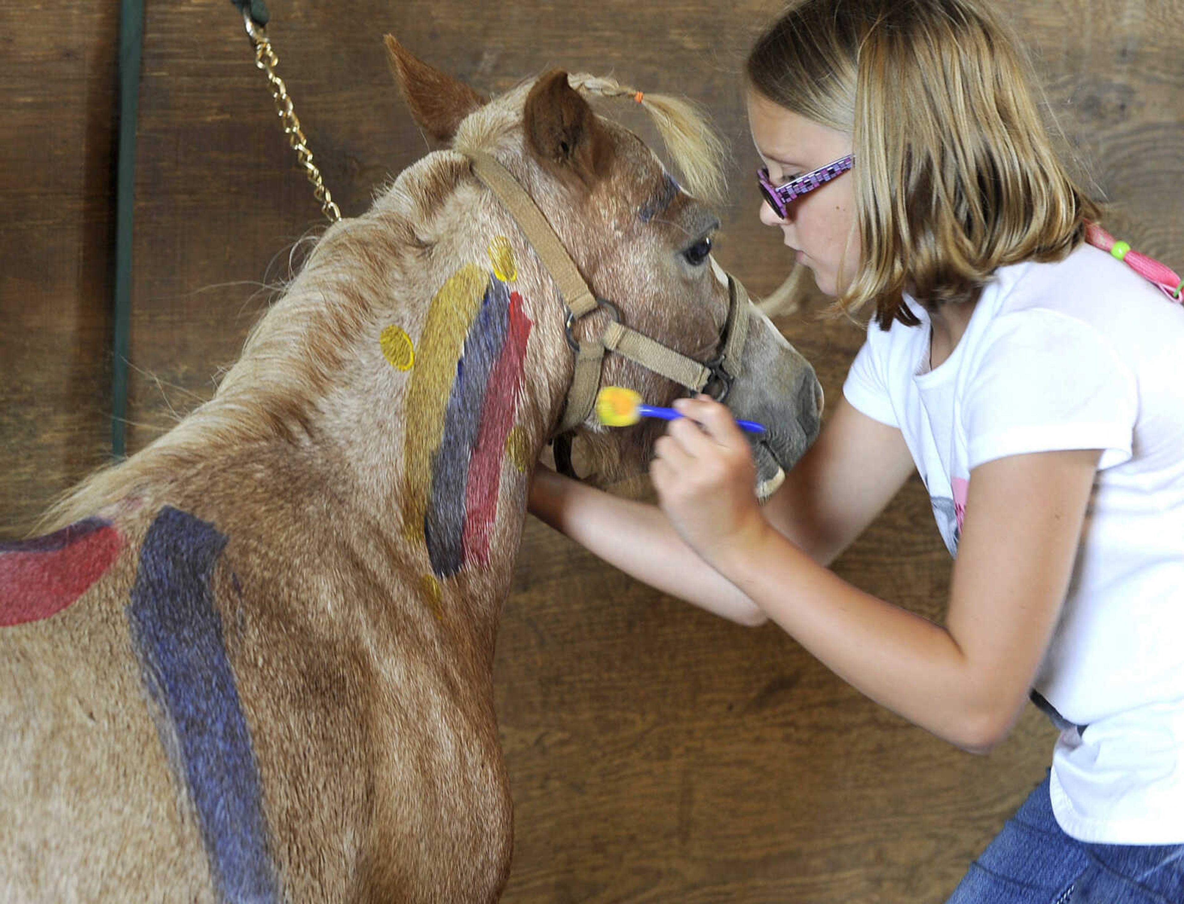 FRED LYNCH ~ flynch@semissourian.com
Hannah Strothmann decorates Ruby with paint after washing the miniature horse and braiding her mane, during a horseback riding camp Monday, July 6, 2015 at Rolling Hills Farm west of Cape Girardeau.