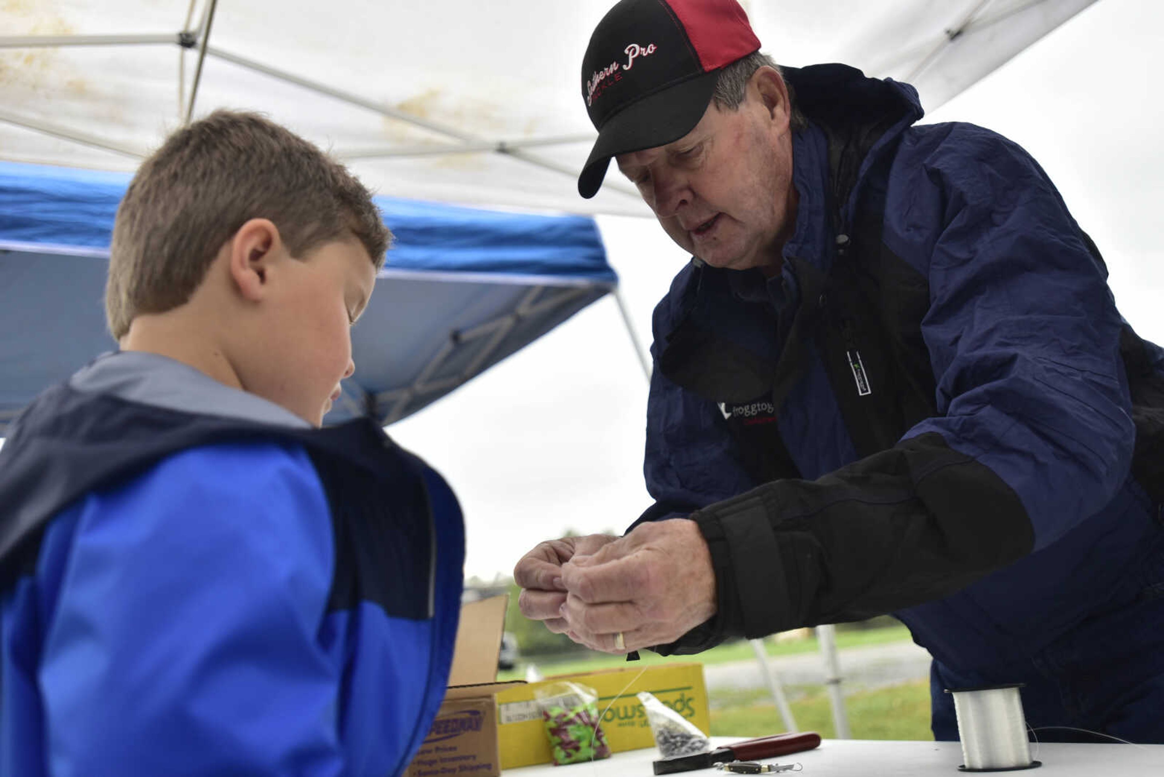 Charlie Rogers teaches 7-year-old Jordan Burnett about fishing lures at a booth during the inaugural Fishing Rodeo held Oct. 15, 2017 at Elks Lake in Cape Girardeau.