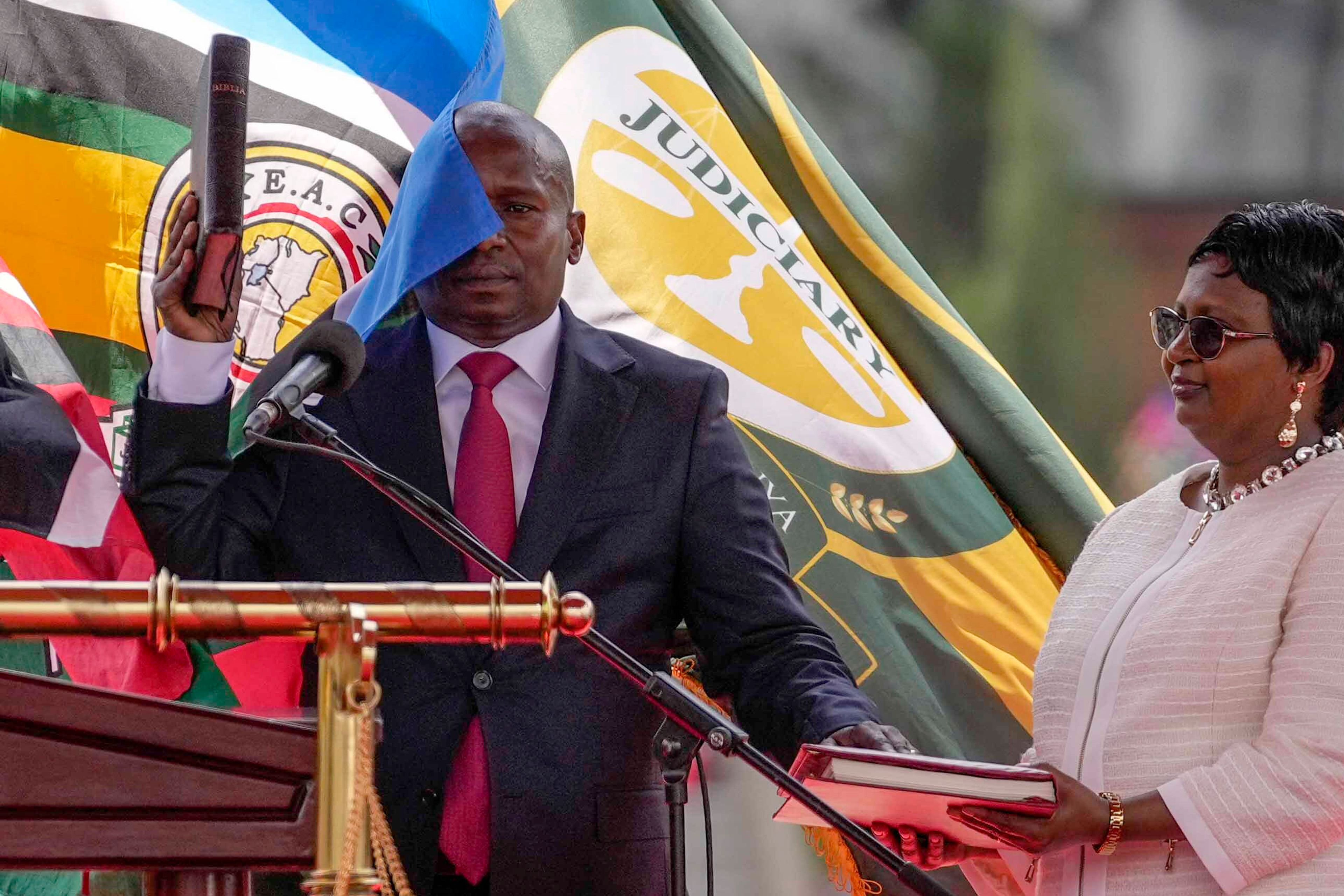 Kenya's new Deputy President Kithure Kindiki, left, is sworn into office as his wife Joyce Kithure, right, holds the Bible at a ceremony held at Kenyatta International Convention Centre, in Nairobi, Kenya Friday, Nov. 1, 2024. (AP Photo/Brian Inganga)