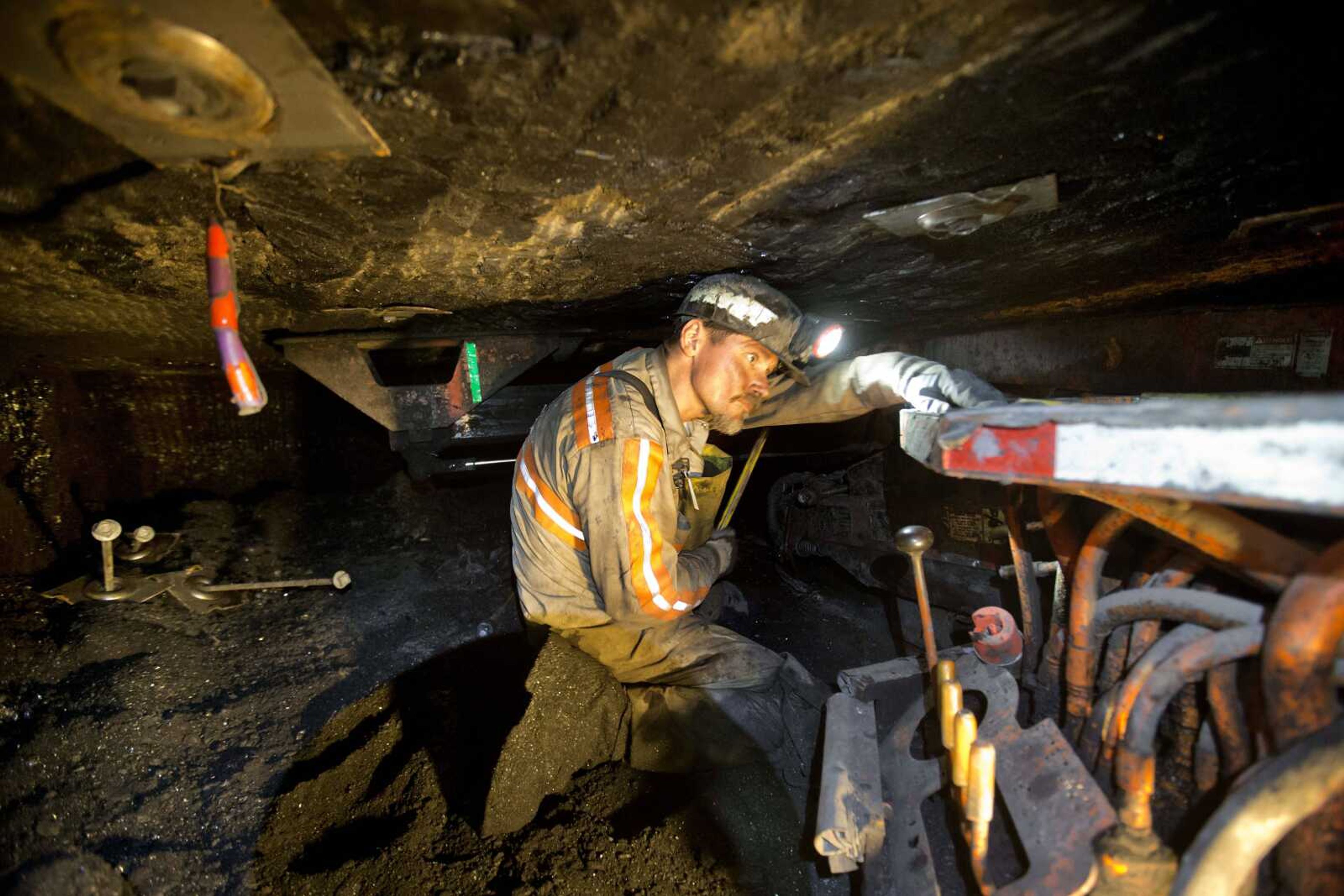 Scottie Stinson, a coal miner of 16 years, works Oct. 6 to secure the roof with bolts in an underground coal mine roughly 40 inches high in Welch, West Virginia. Preliminary government figures released Friday show U.S. coal production has fallen to its lowest level in nearly 30 years. (David Goldman ~ Associated Press)