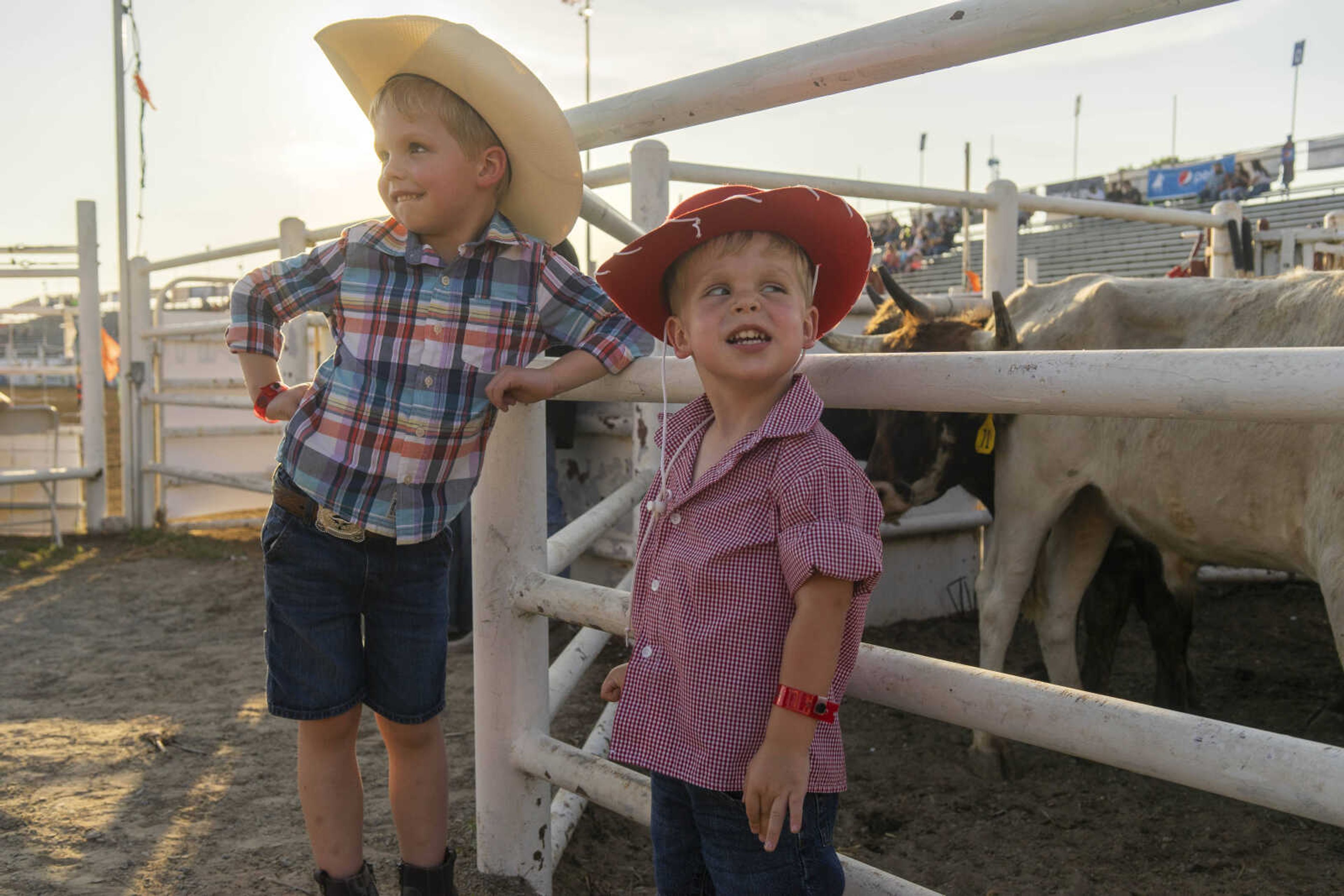 Eddie Hendrick, left, smiles at his mother while his brother, Theo, sneaks a glance at the livestock during the Sikeston Jaycee Bootheel Rodeo on Thursday, Aug. 12, 2021, in Sikeston, Missouri.