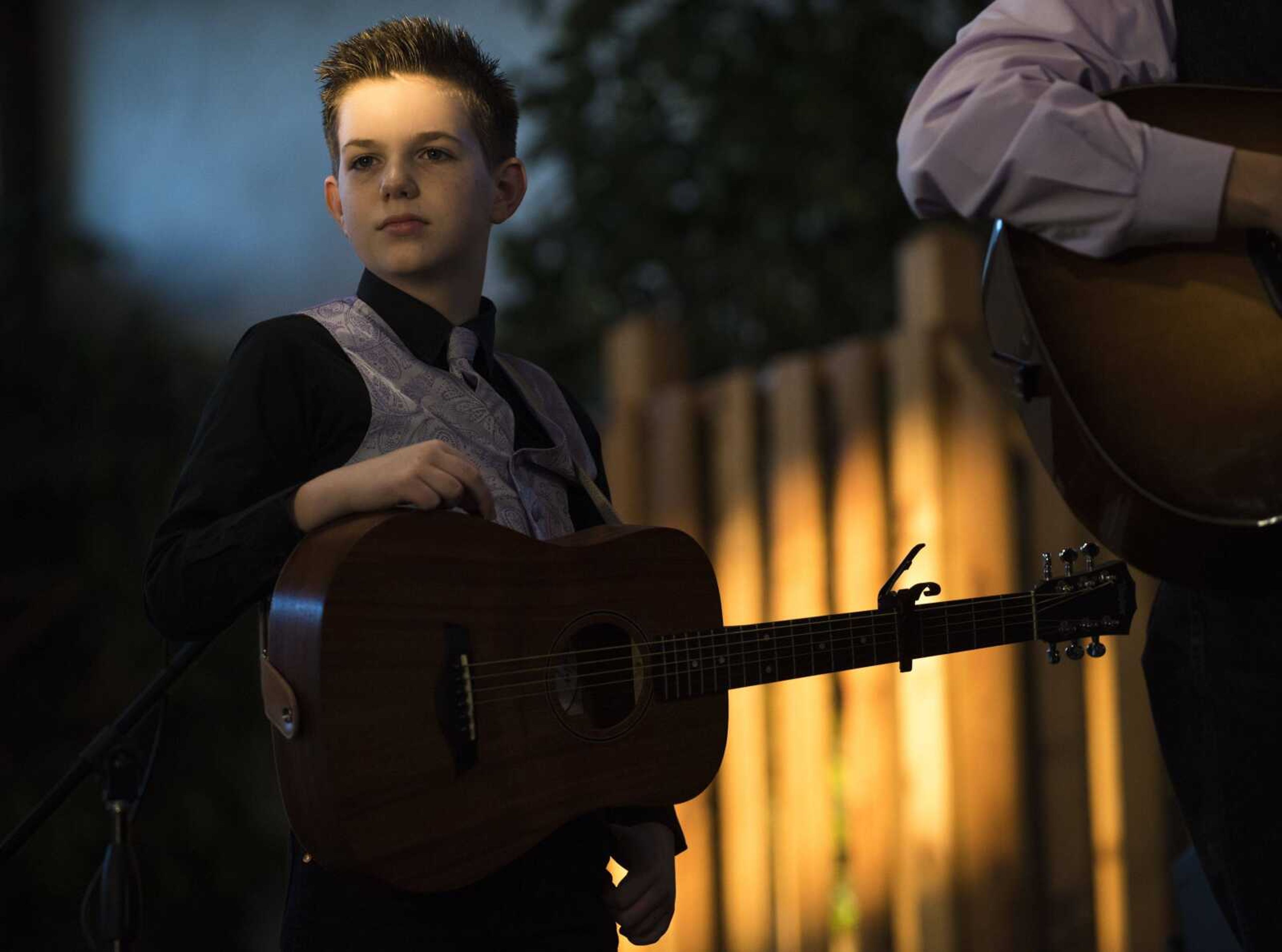 A ray of sunlight partially illuminates the face of Justus Sowell, 11, as he performs with The Family Sowell at the Bootheel Bluegrass Festival Friday at Bavarian Halle in Jackson.