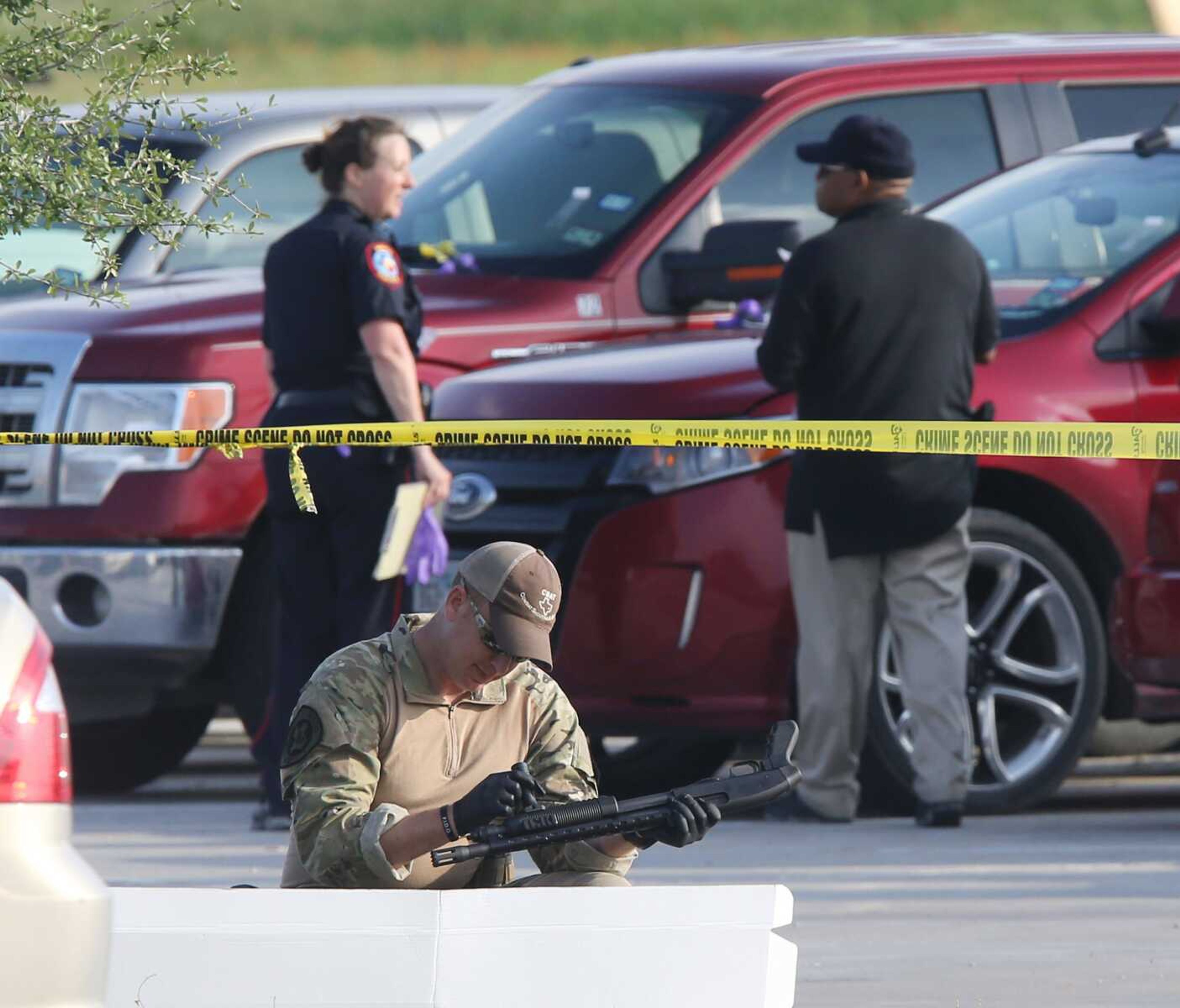 A police officer recovers a rifle while sweeping through the parking lot of a Twin Peaks restaurant Tuesday in Waco, Texas, where a deadly shootout between motorcycle gangs occurred. (Waco Tribune-Herald)