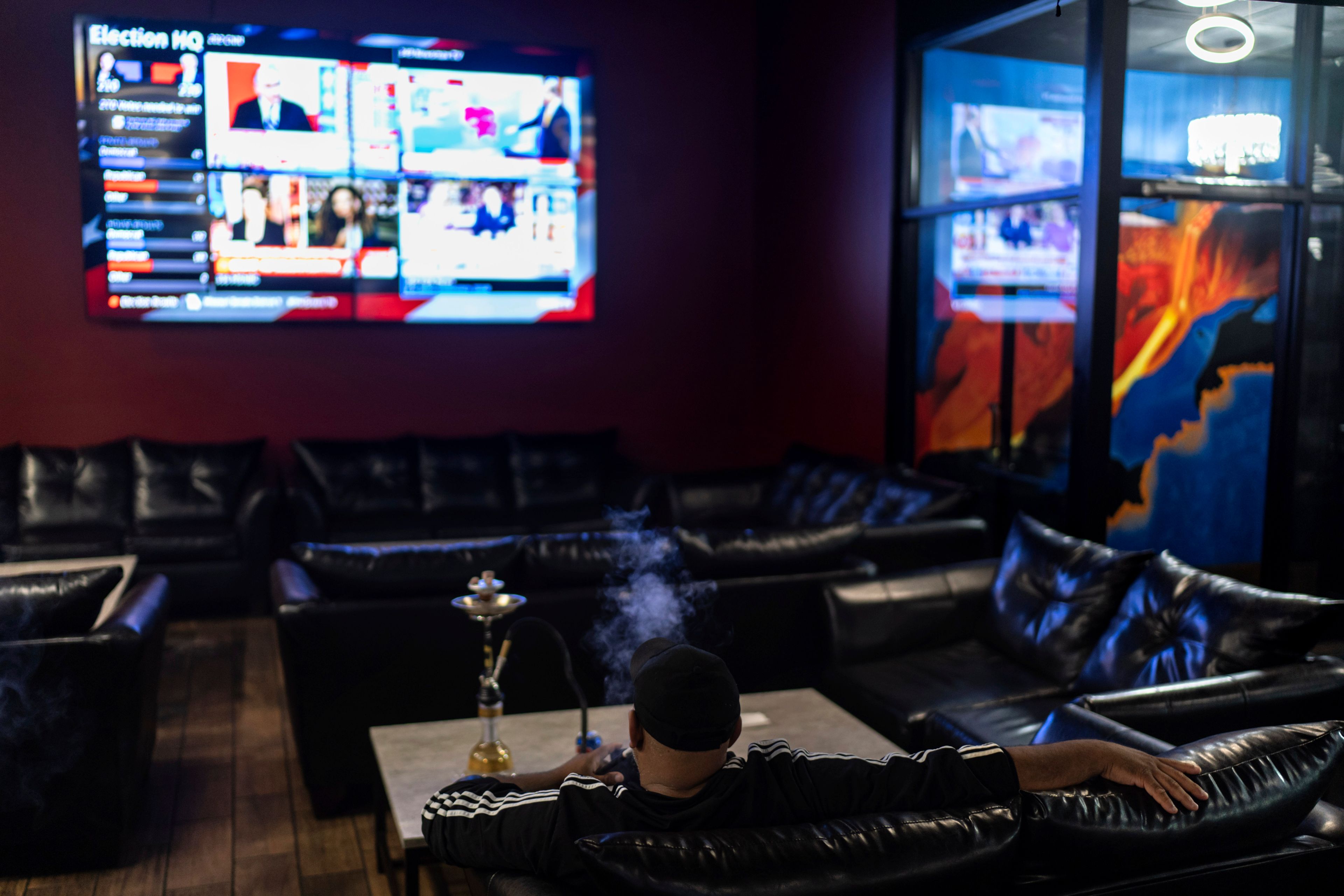 A supporter of Republican presidential nominee former President Donald Trump watches election results at an Arab Americans for Trump watch party at the Lava Java Cafe, a hookah lounge, in the early hours of Wednesday, Nov. 6, 2024, in Dearborn, Mich. (AP Photo/David Goldman)