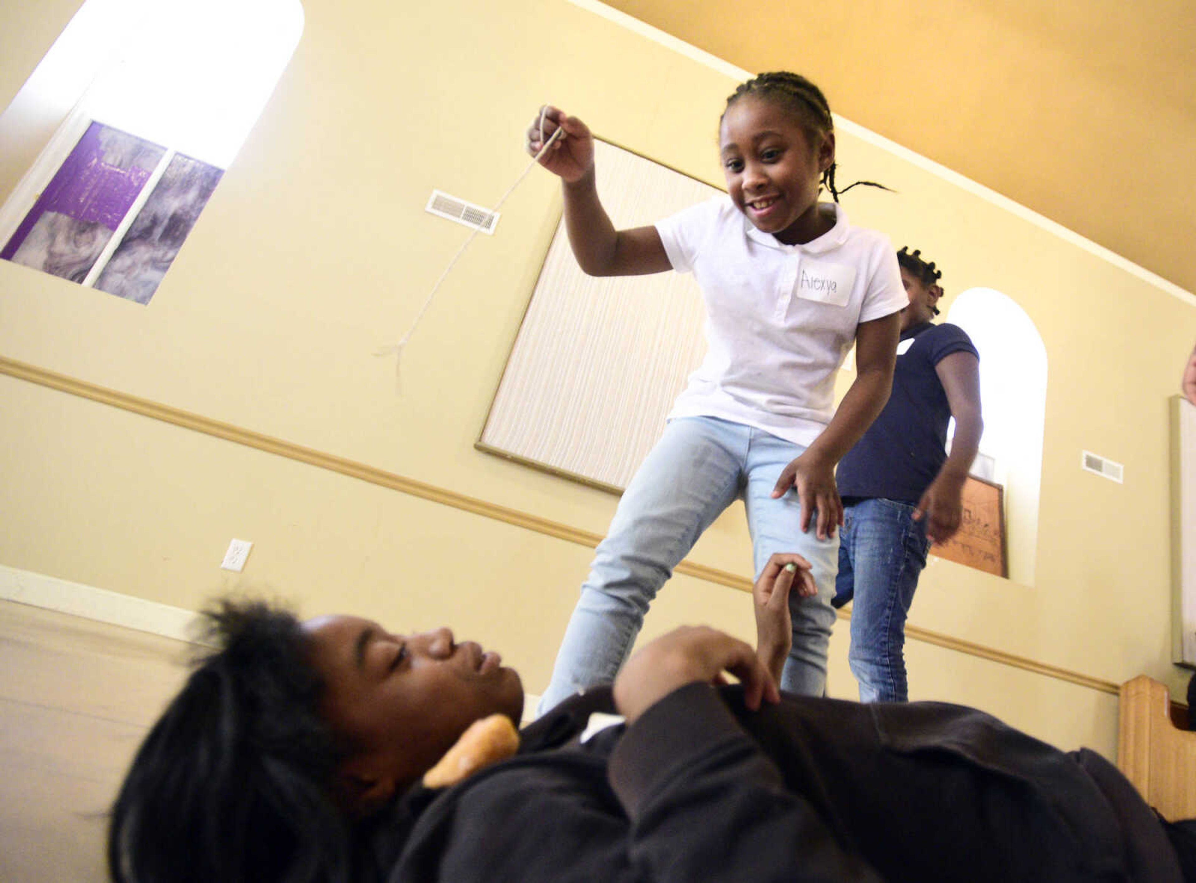 Alexya Jones dangles a donut above GeGe Green on Monday, Aug. 14, 2017, during the Salvation Army's after school program at The Bridge Outreach Center in Cape Girardeau.