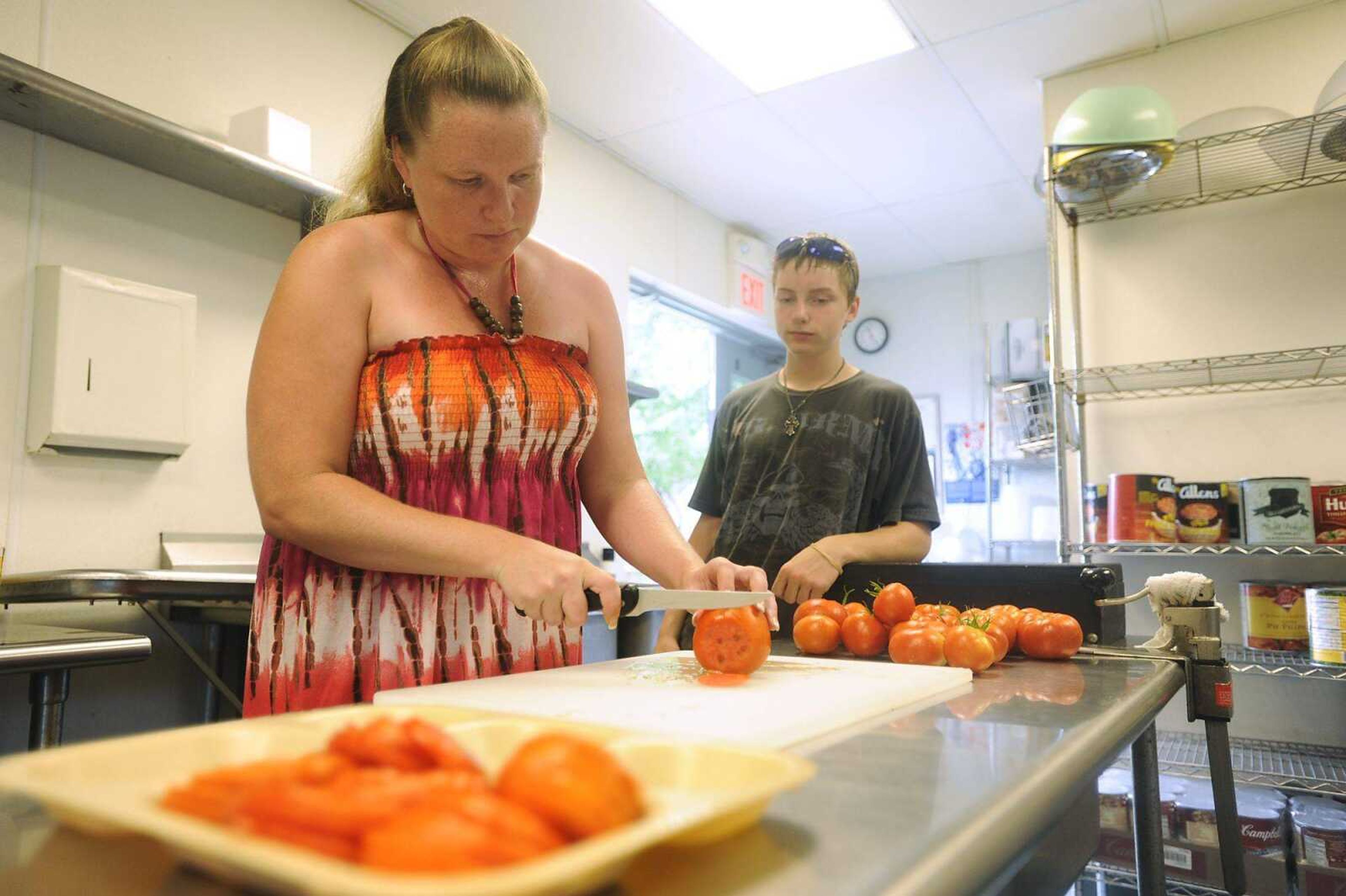 William Ingram, 13, watches as his mother, Joanna Howard, slices tomatoes for the Missouri Department of Youth Services' Family Day on July 14. The tomatoes were grown by the students at the Cape Girardeau facility in a garden they maintain. (ADAM VOGLER)