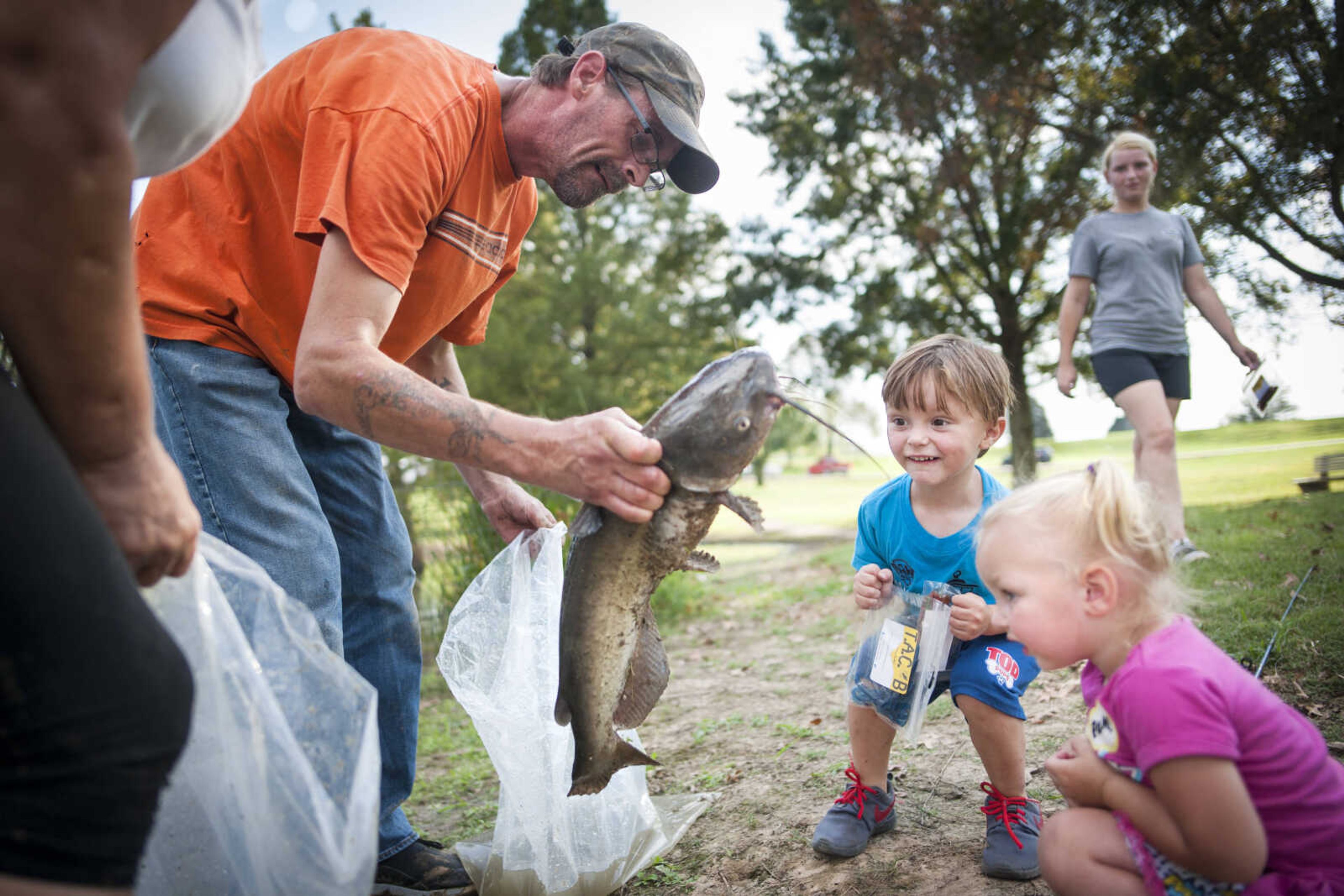 Jeremy Green, left, helps bag a catfish caught by Lanie Mills, 2, bottom right, as she crouches next to her brother, Ryley Mills, 3, during the third annual Fishing Rodeo hosted by the Fraternal Order of Police Lodge 51 on Sept. 29, 2019, at Cape County Park North in Cape Girardeau. The 6.49 pound catfish was the largest catch of the event.