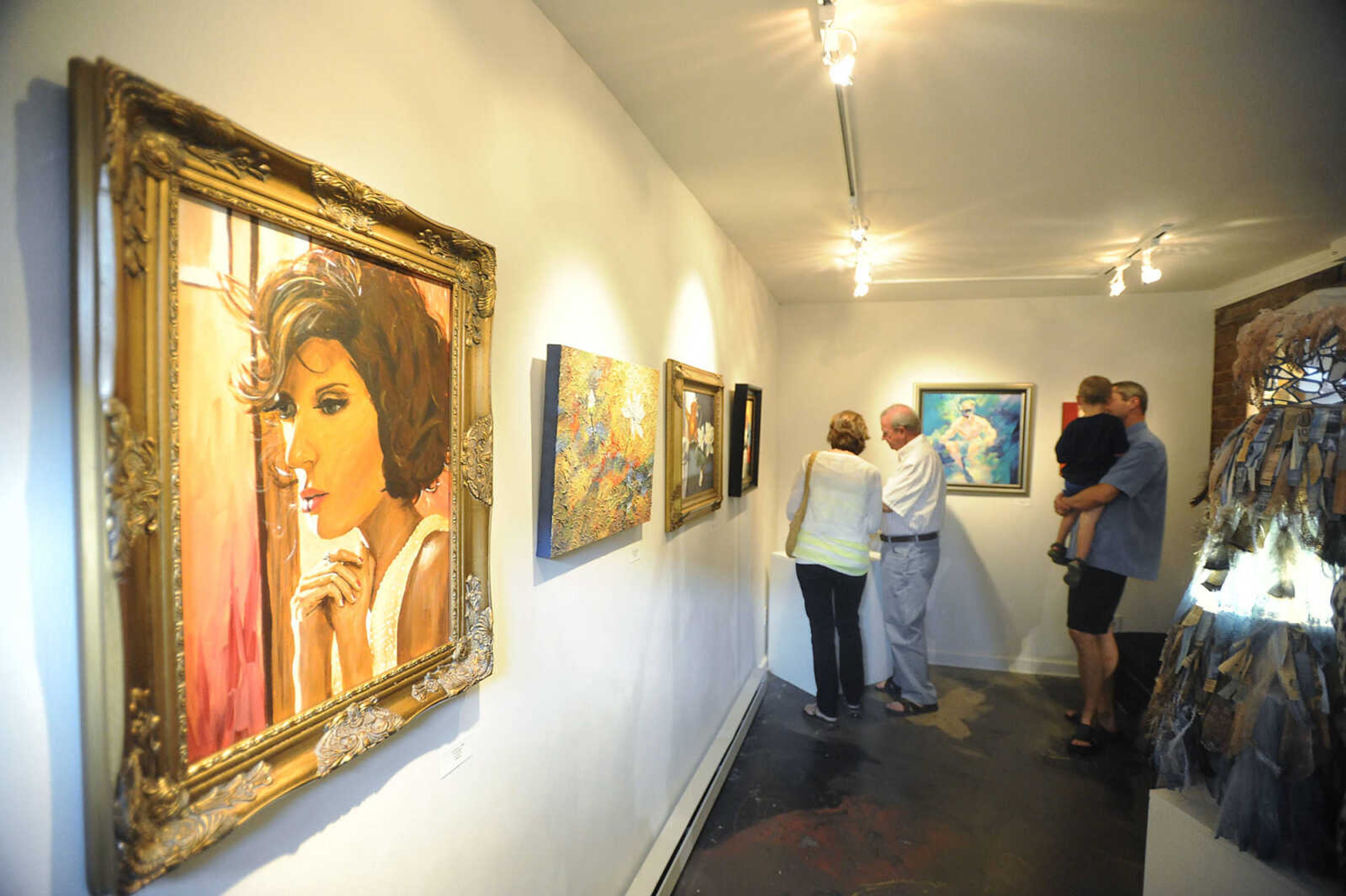 Attendees look at the work of 37 female artists during the opening for "Feminine Perspectives," at the Black Dog Gallery during First Friday. The first Friday of each month galleries in Downtown Cape Girardeau hold openings from 5 p.m to 9 p.m. with food, drink and the opportunity to talk with the artists about their work.