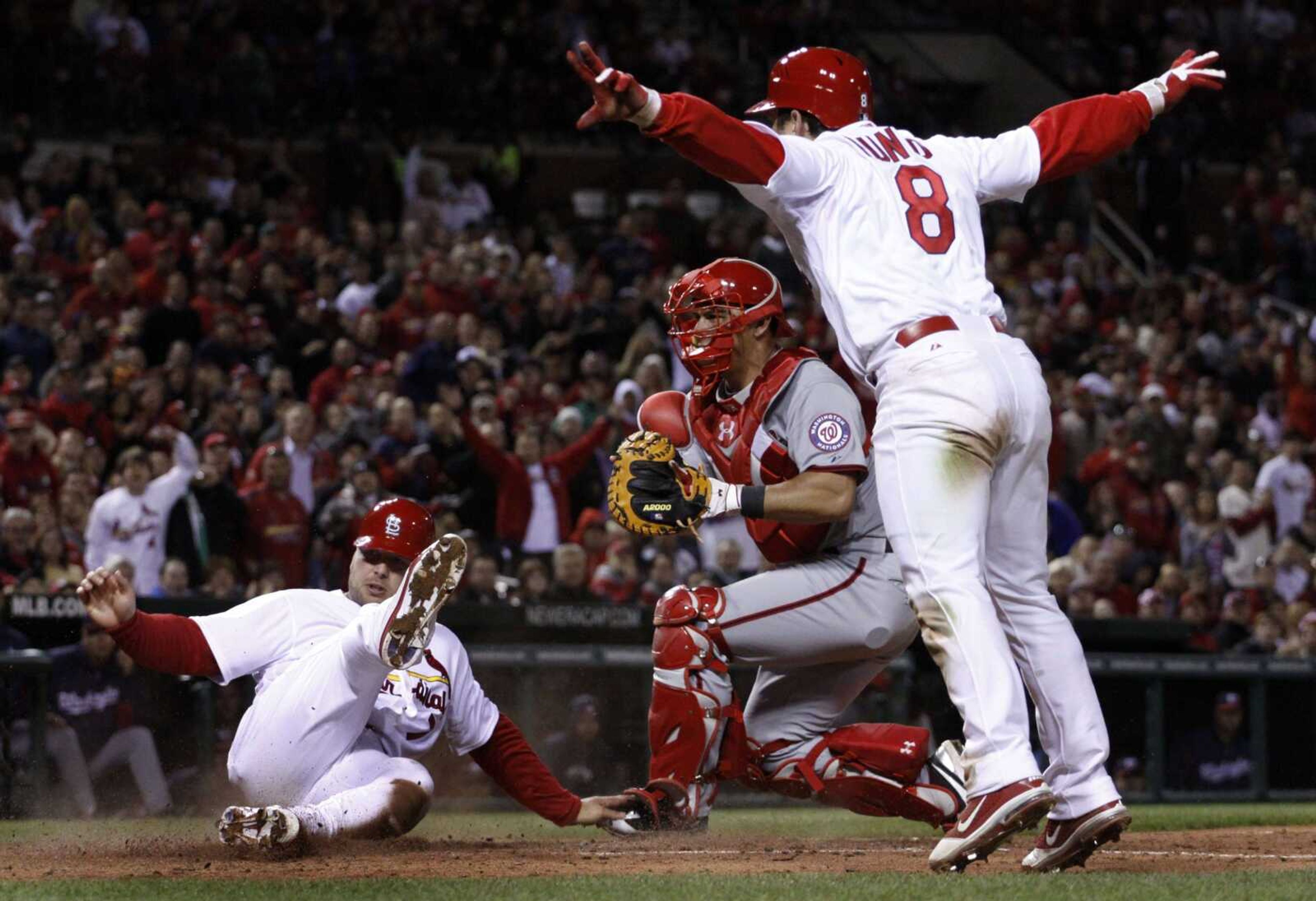 Cardinals baserunner Matt Holliday is safe at home after avoiding the tag from Nationals catcher Wilson Ramos as Cardinals infielder Nick Punto looks on during the fifth inning of the second game of Wednesday's doubleheader in St. Louis. (JEFF ROBERSON ~ Associated Press)