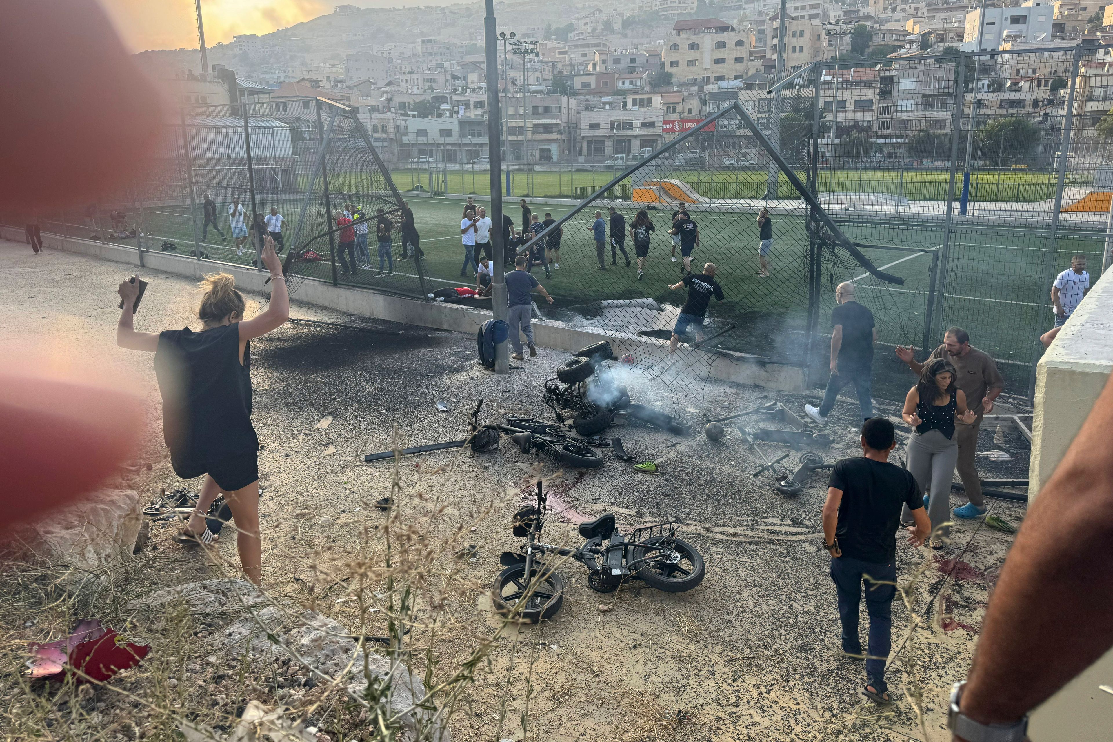 Residents rush to help injured children moments after a rocket attack hit a soccer field in the Druze town of Majdal Shams in the Israeli-controlled Golan Heights, Saturday, July 27, 2024. (AP Photo/Hassan Shams)