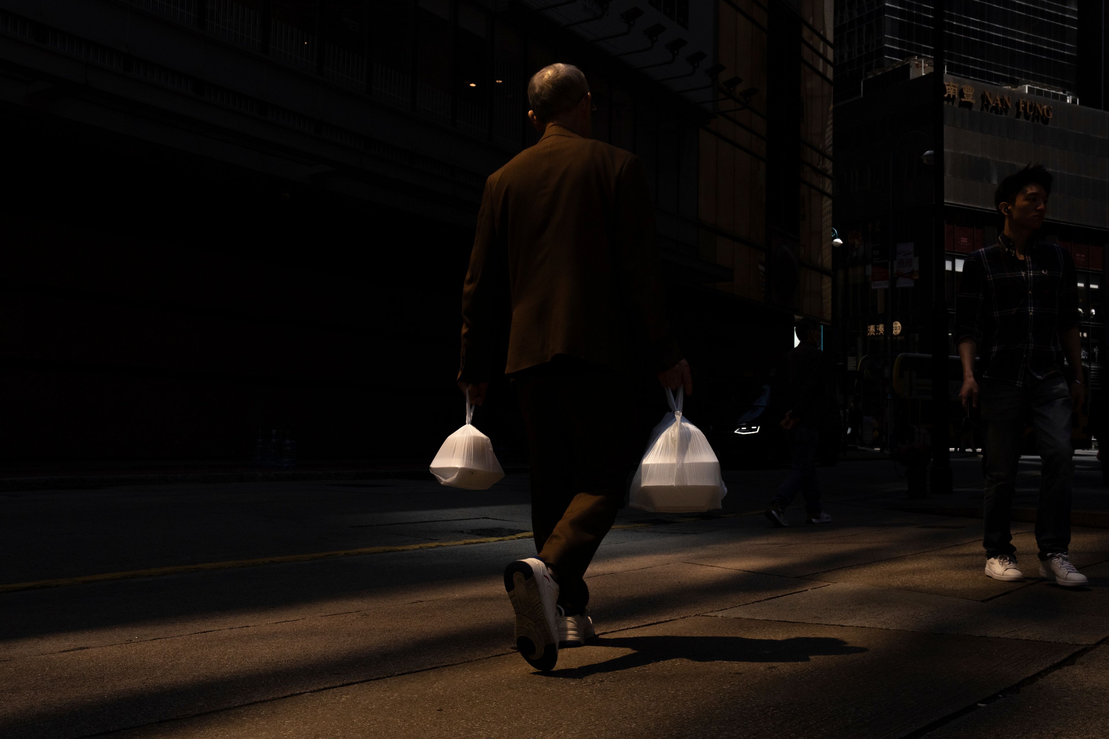 FILE- A pedestrian carries takeaway food plastic bags in Hong Kong, Wednesday, March 13, 2024. (AP Photo/Louise Delmotte, File)