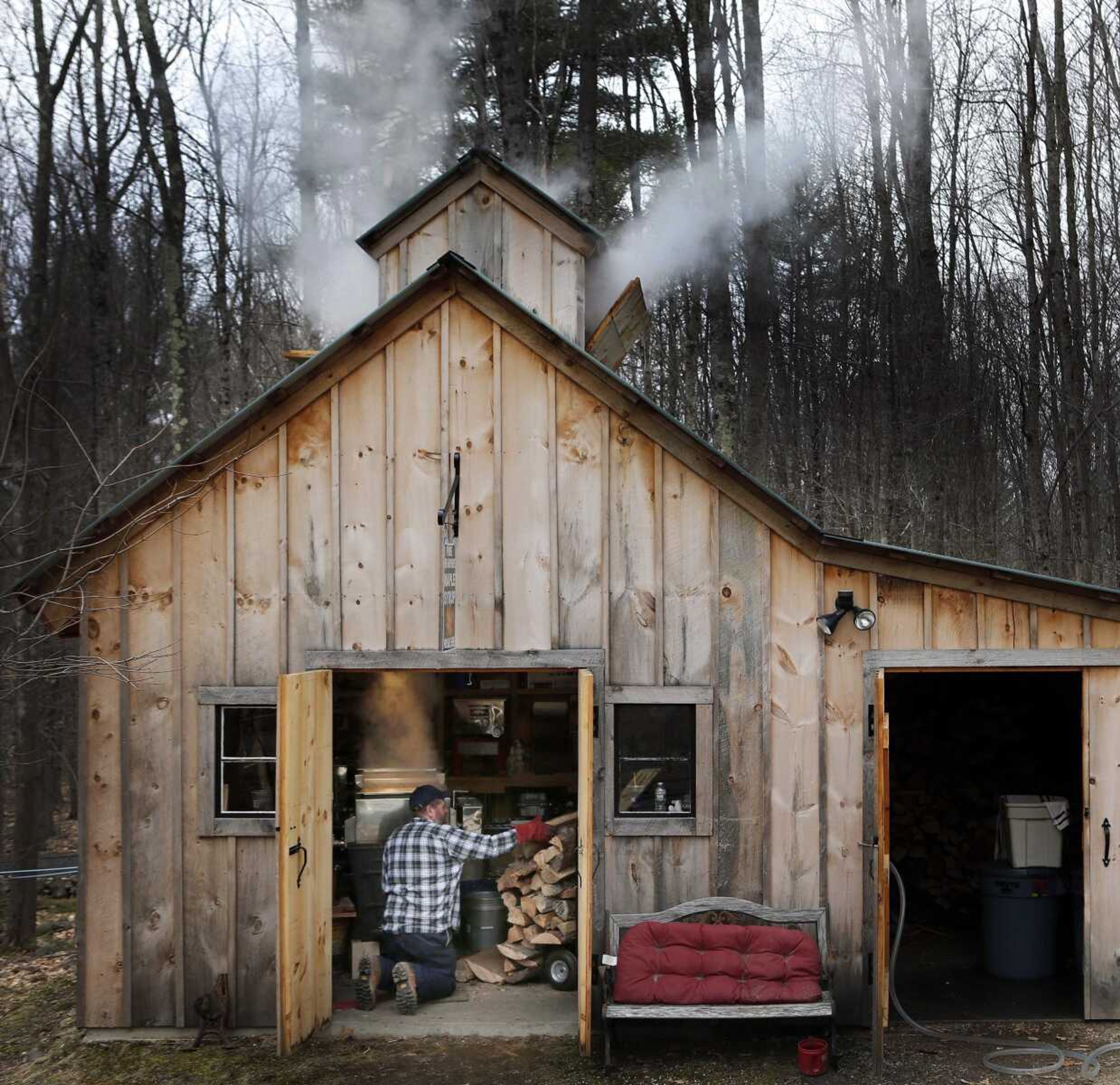 Jason Landry loads wood into the firebox as he boils down sap at his sugarhouse to make maple syrup March 10, 2016, in Loudon, New Hampshire.