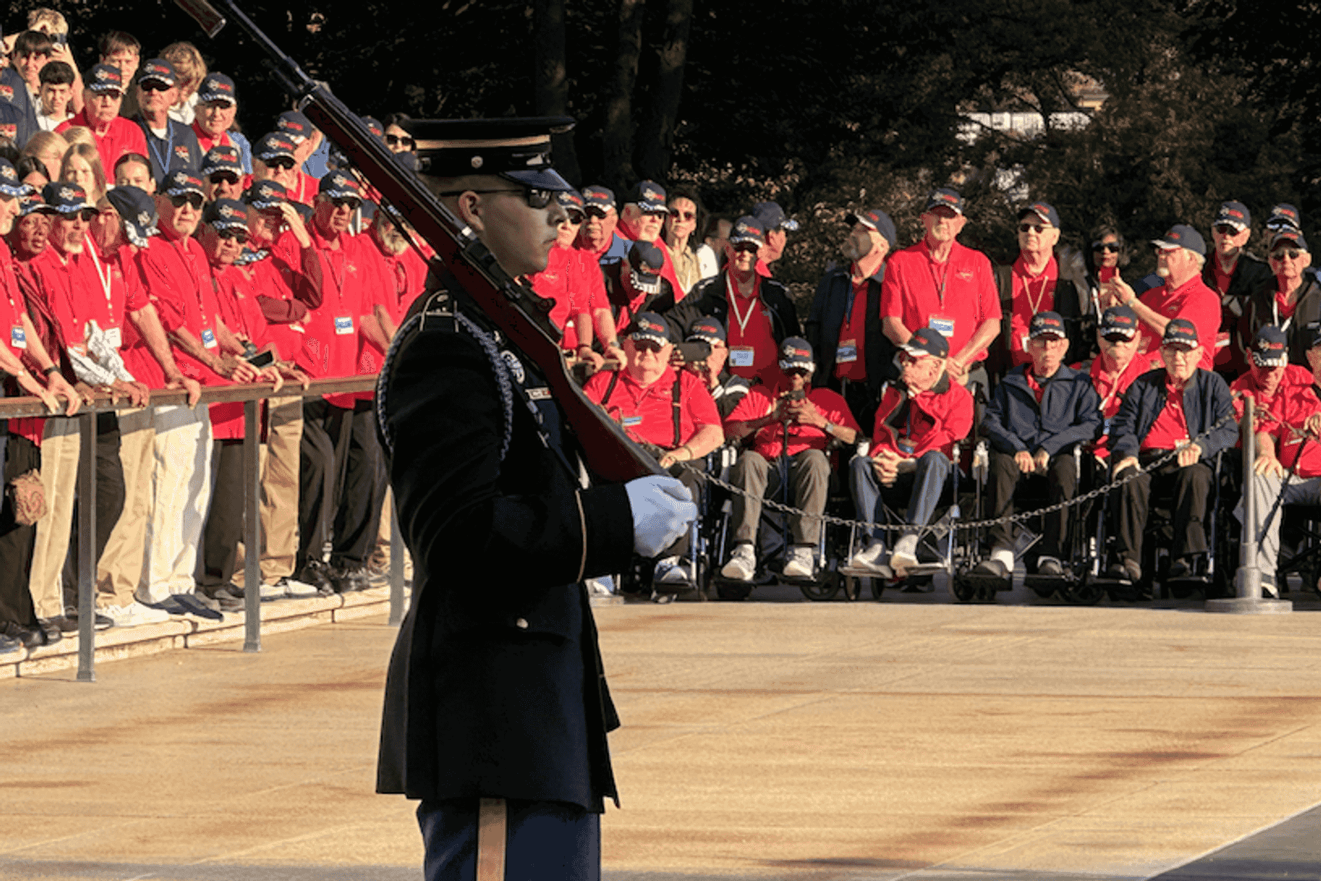 A sentinel stands guard at the Tomb of the Unknown Soldier in Arlington, Va., as veterans from another Honor Flight watch.