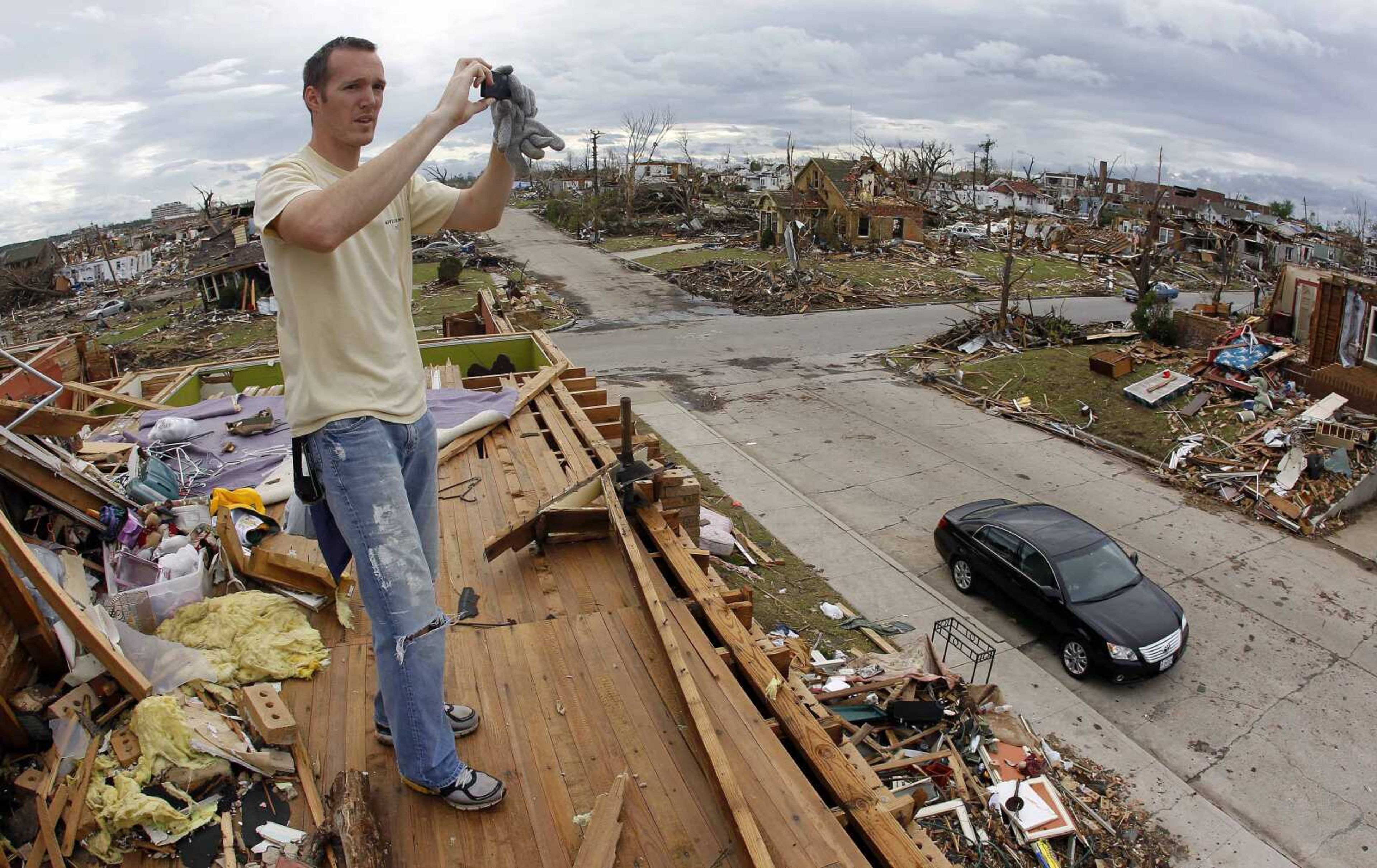 Jacob Williams photographs the neighborhood from what used to be the second story of his aunt's home on Wednesday, May 25, 2011, in Joplin, Mo. A tornado tore through much of the city Sunday, wiping out neighborhoods and killing at least 123 people. (AP Photo/Mark Humphrey)