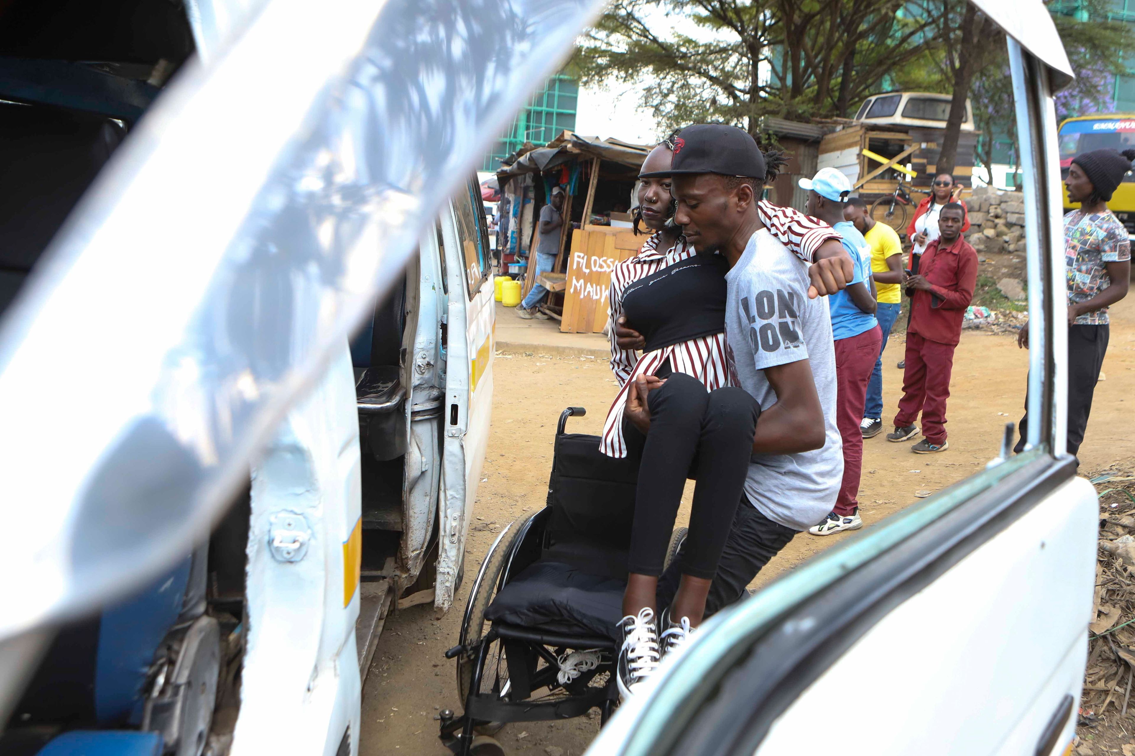 A man helps Carol Mwikali to get inside a public transport vehicle in Nairobi, Kenya, Wednesday, Oct. 9, 2024. (AP Photo/Andrew Kasuku)