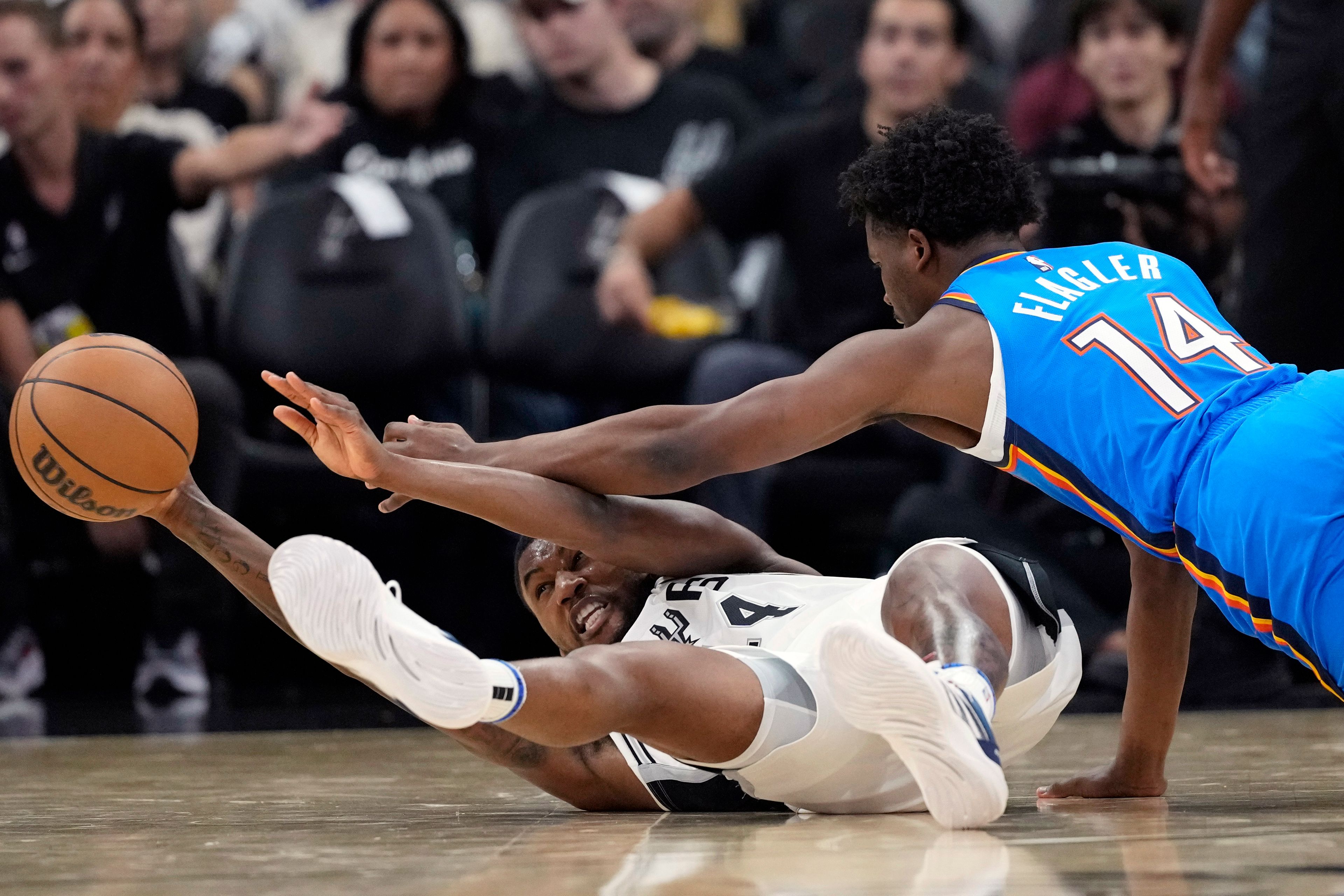 San Antonio Spurs guard Blake Wesley, left, and Oklahoma City Thunder forward Adam Flagler, right, scramble for a loose ball during the second half of a preseason NBA basketball game in San Antonio, Monday, Oct. 7, 2024. (AP Photo/Eric Gay)