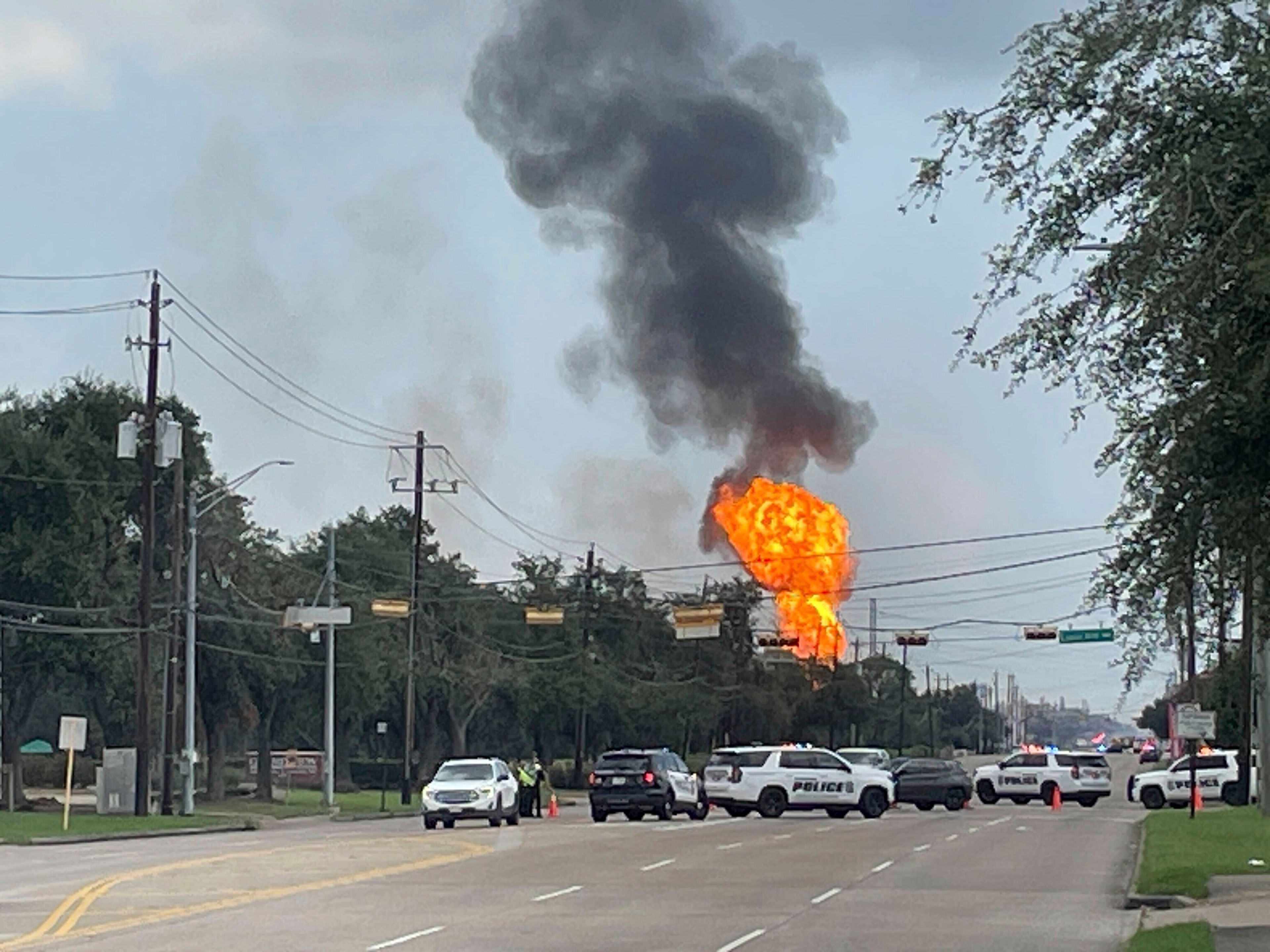 Police block off a highway as a large fire from a pipeline explosion burns near La Porte, Texas, on Monday, Sept. 16, 2024. (AP Photo/Lekan Oyekanmi)