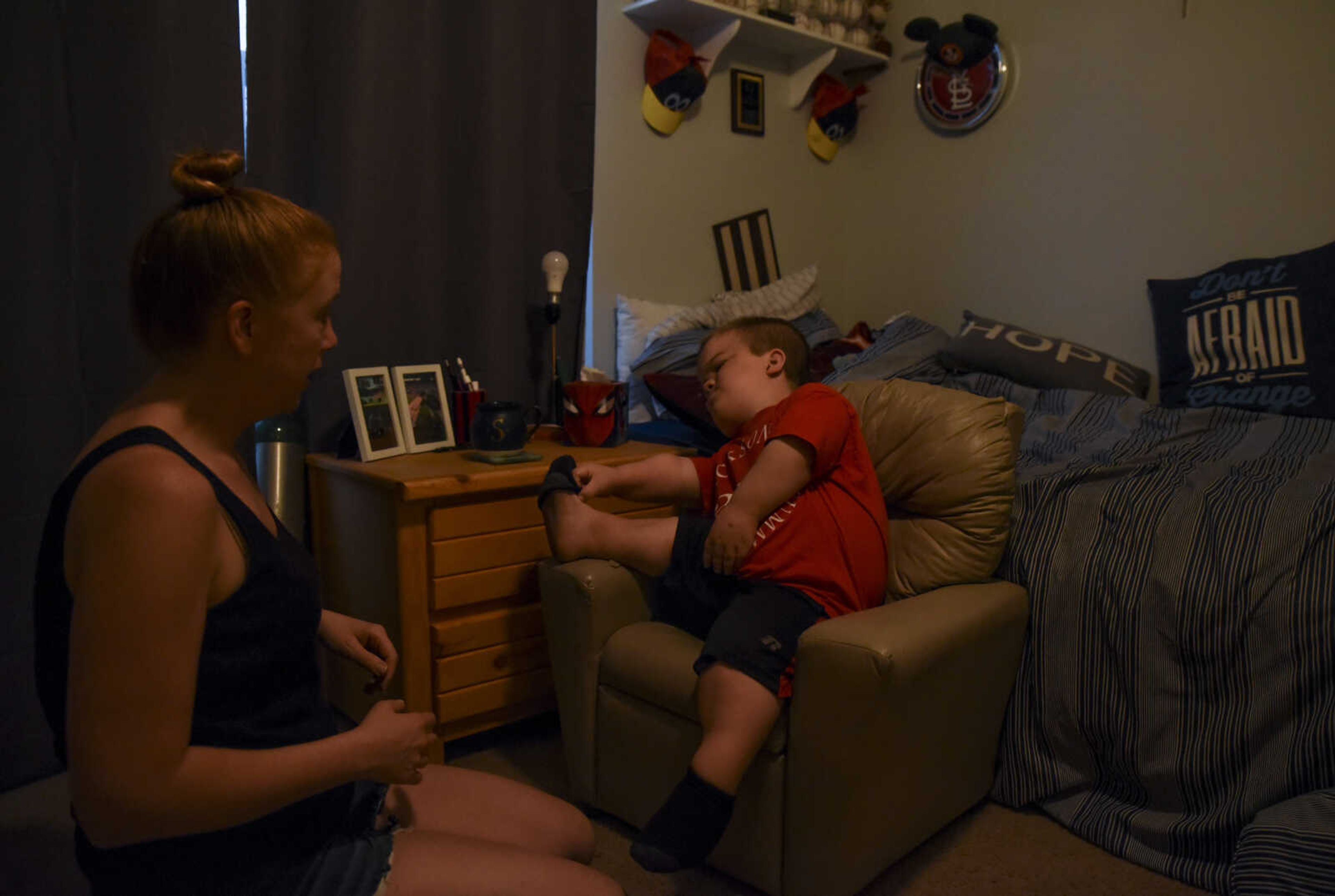 Izaac Pursley struggles to put his sock on on his own, while his mom Sheree Pursley waits to help him as he prepares for school May 3, 2018, in their Jackson home. Because of Izaac's shortened bone growth, he struggles to perform daily tasks such as dressing himself easily.