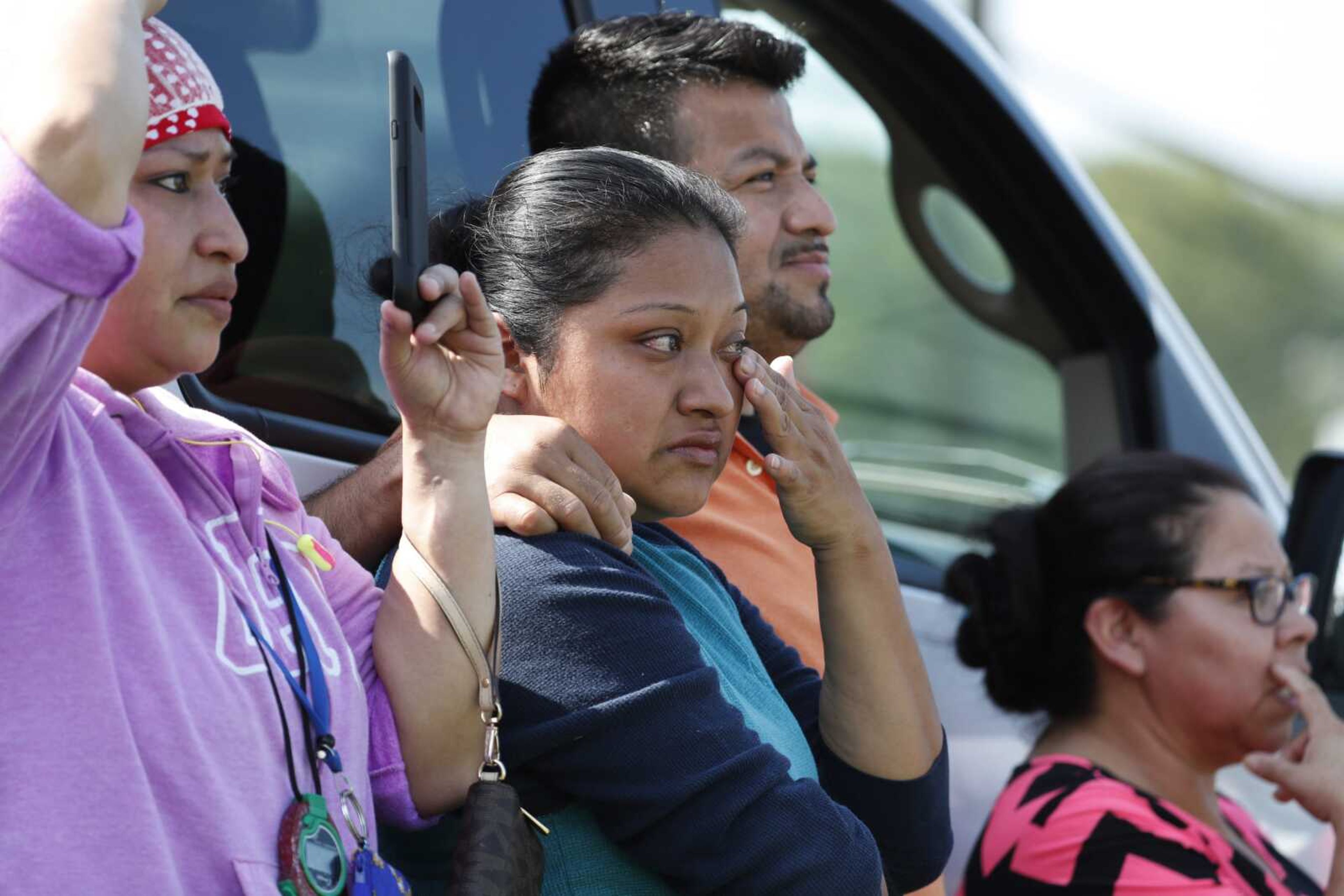 Friends, coworkers and family watch as U.S. immigration officials raid the Koch Foods Inc. plant Wednesday in Morton, Mississsippi.  U.S. immigration officials raided several Mississippi food processing plants Wednesday and signaled that the early-morning strikes were part of a large-scale operation targeting owners as well as employees.