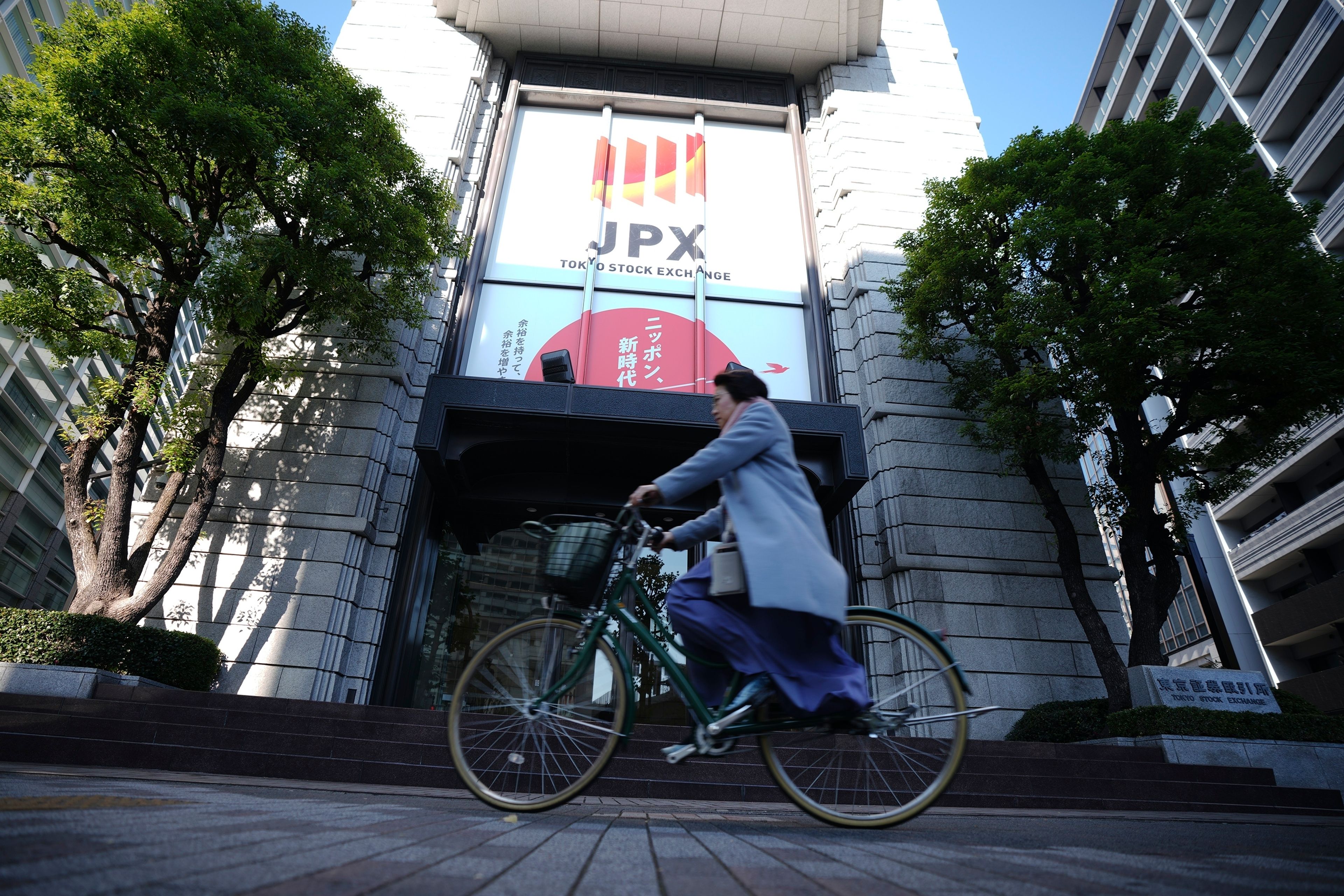 A person rides a bicycle in front of Tokyo Stock Exchange building Tuesday, Dec. 3, 2024, in Tokyo. (AP Photo/Eugene Hoshiko)