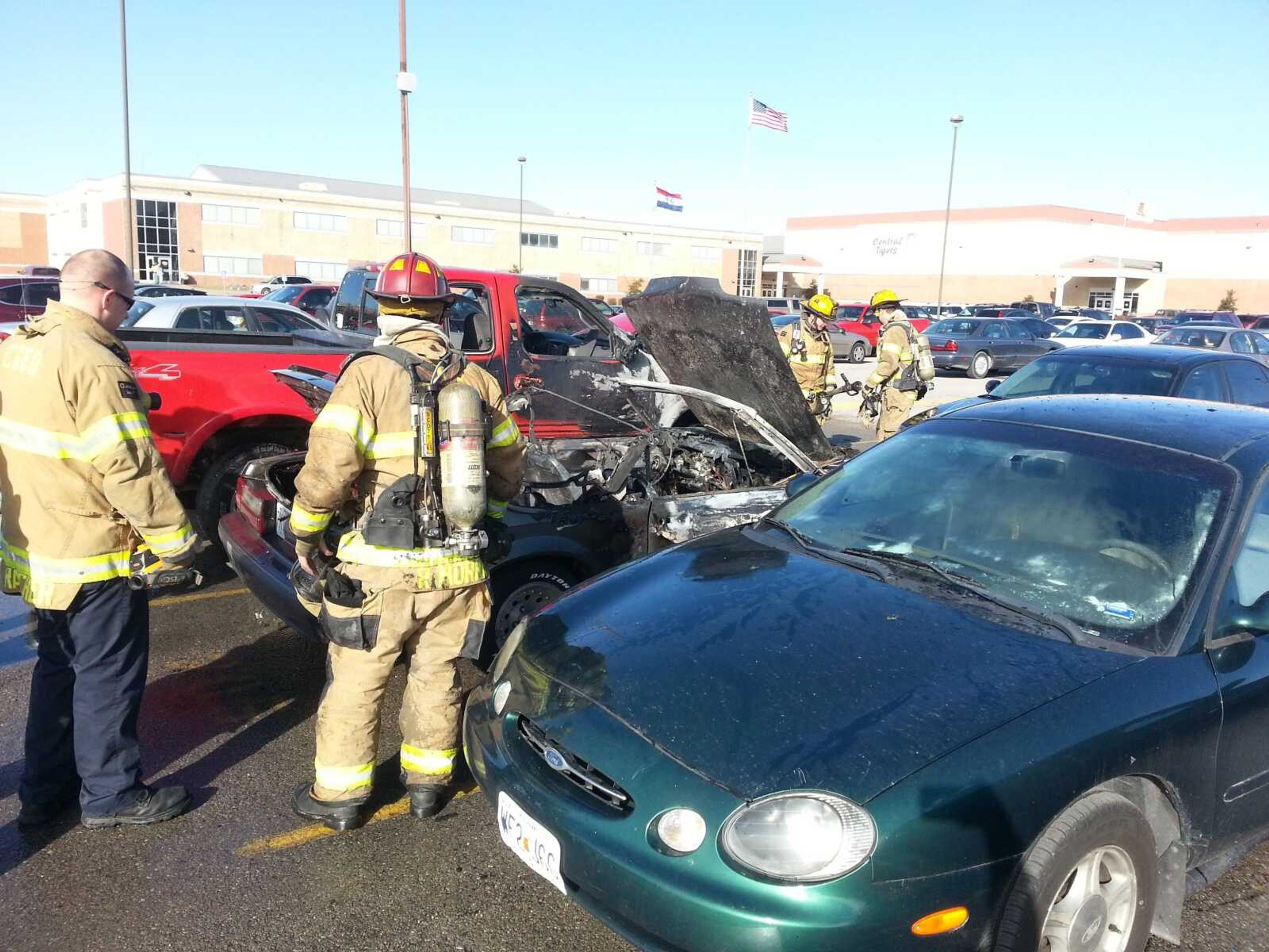 Firefighters contain a vehicle fire that started with one vehicle, a Ford Mustang, and spread to two other vehicles in the parking lot of Cape Central High School. The cause of the fire has not been determined.