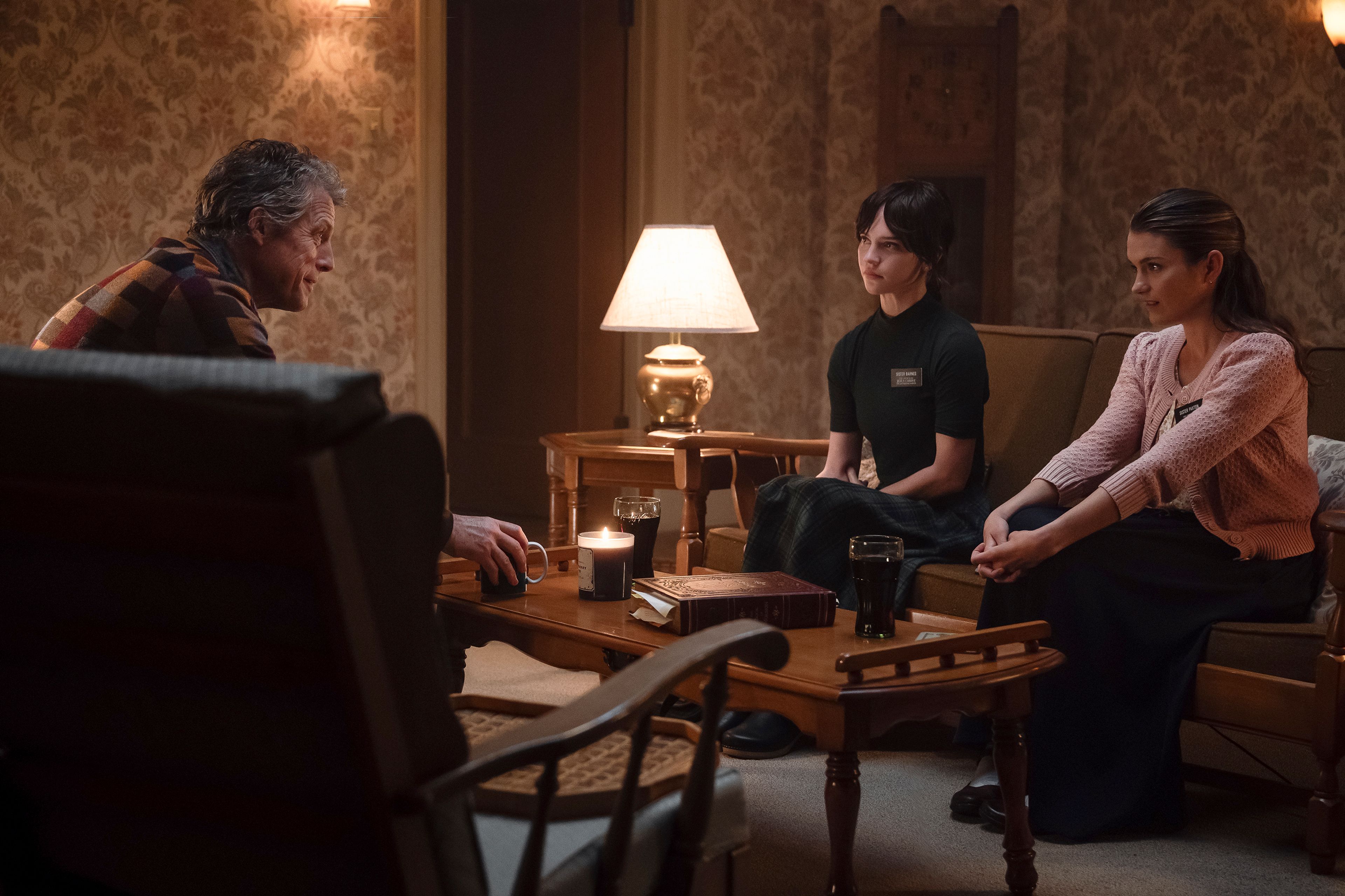 This image released by A24 shows Hugh Grant, from left, Sophie Thatcher and Chloe East in a scene from "Heretic." (Kimberley French/A24 via AP)