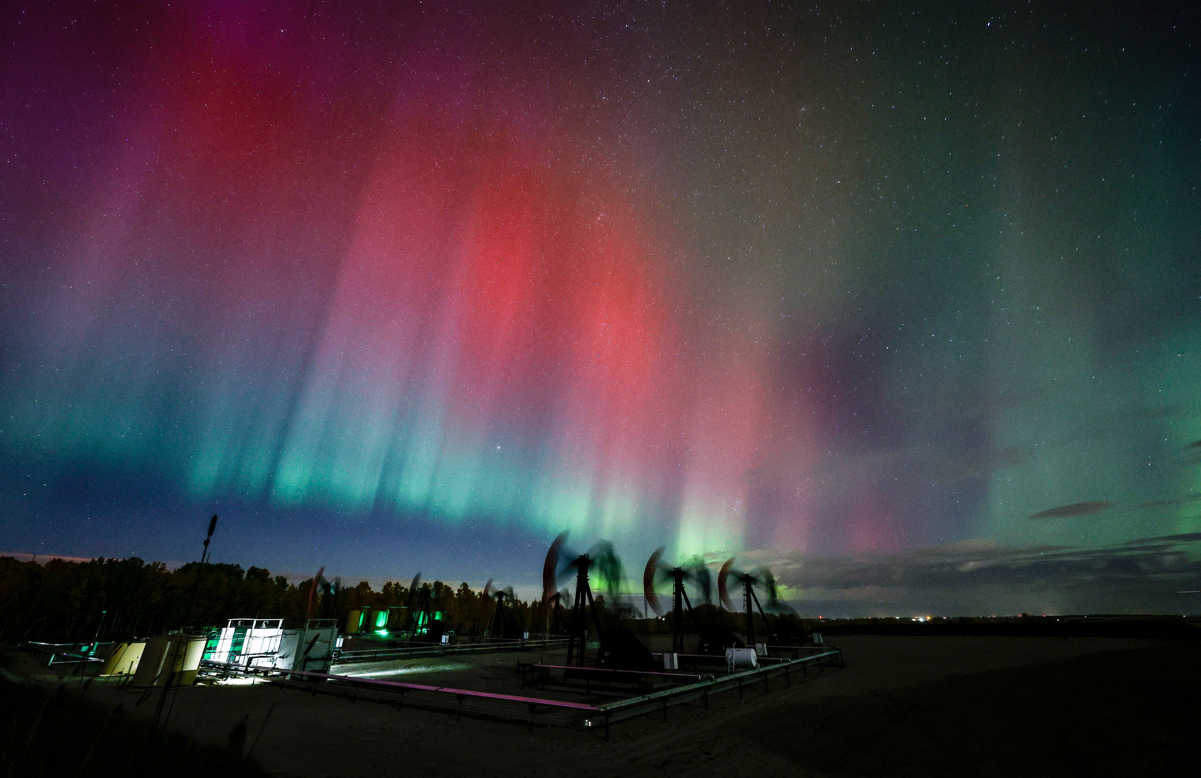 An aurora borealis, also known as the northern lights, makes an appearance over pumpjacks as they draw out oil and gas from well heads near Cremona, Alberta, Thursday, Oct. 10, 2024. (Jeff McIntosh/The Canadian Press via AP)